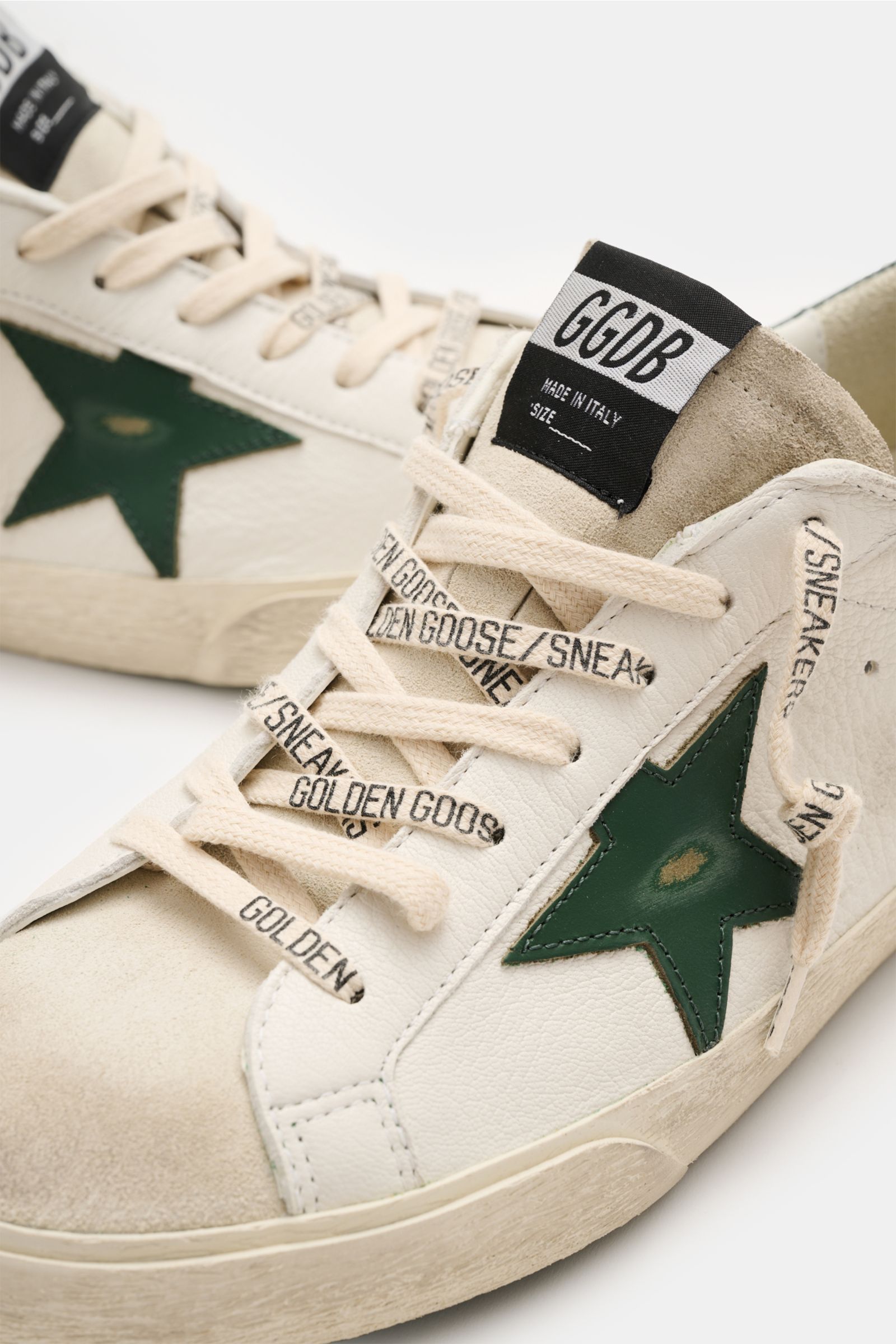 Golden Goose Sneaker 'Super-Star Classic' offwhite/dunkelgrün in Nahaufnahme von schräg oben, mit Vintage-Finish, Nappaleder, Stern, Used-Optik und handgemachten Details.