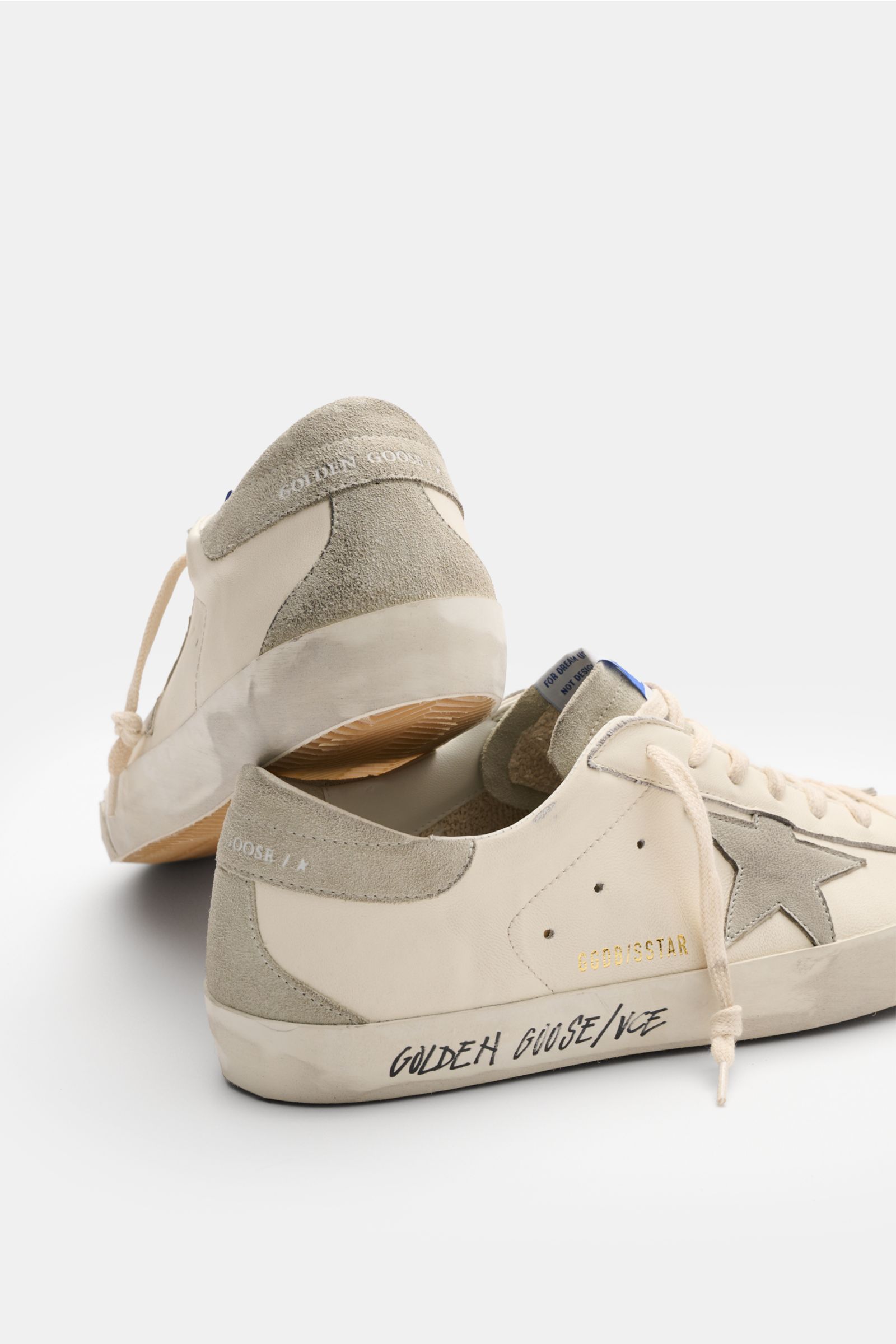 Golden Goose Sneakers 'Super-Star Classic' off-white/light grey shown from a rear side angle with vintage finish, suede star, and handmade used-look, featuring fine Napa leather, suede and nubuck overlays, seven-eyelet lacing, perforated sides, suede tong