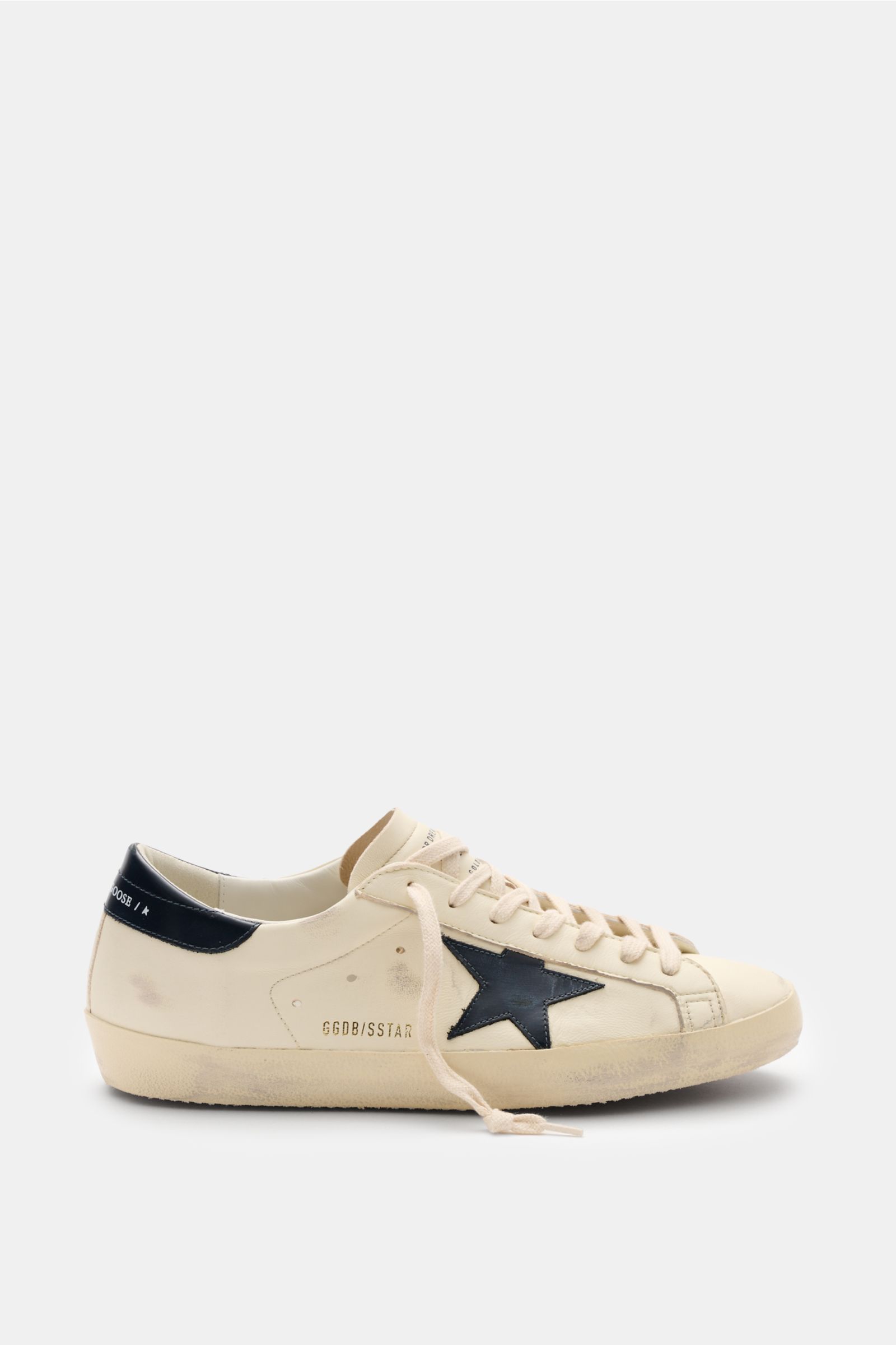 Golden Goose Sneaker 'Super-Star Classic' creme/navy shown from the side with vintage-finish, iconic navy star, hand-made used look, and creme laces. Für alle, die Patina feiern statt Perfektion: Der 'Super-Star Classic' bringt mit Vintage-Finish, dem 