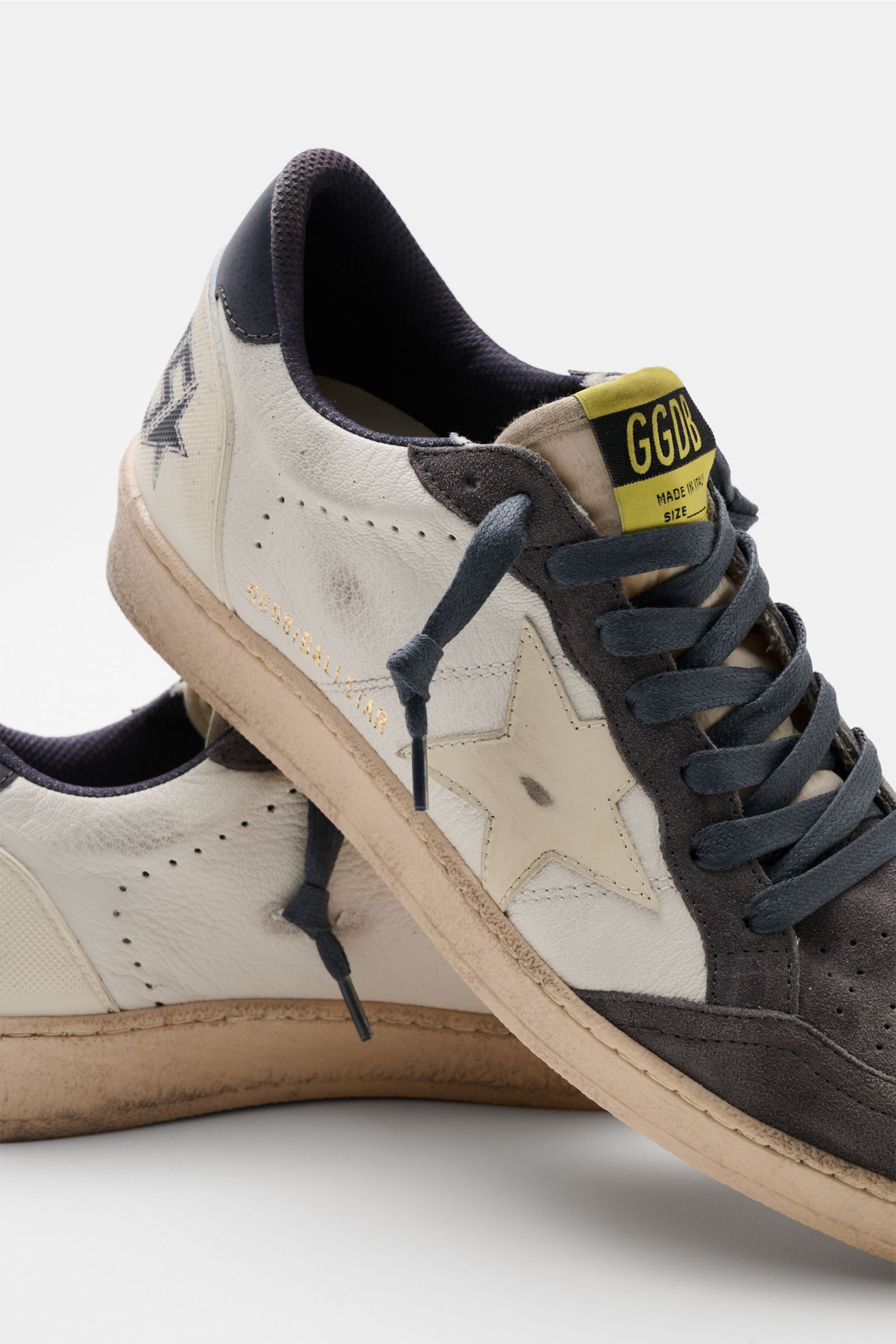 Close-up side and front view of Golden Goose Sneaker 'Ball Star' offwhite/creme/dunkelgrau with vintage finish, iconic star, and used look.

Description: Der 'Ball Star' von GOLDEN GOOSE bringt mit Vintage-Finish, dem ikonischen Stern und handgemachter