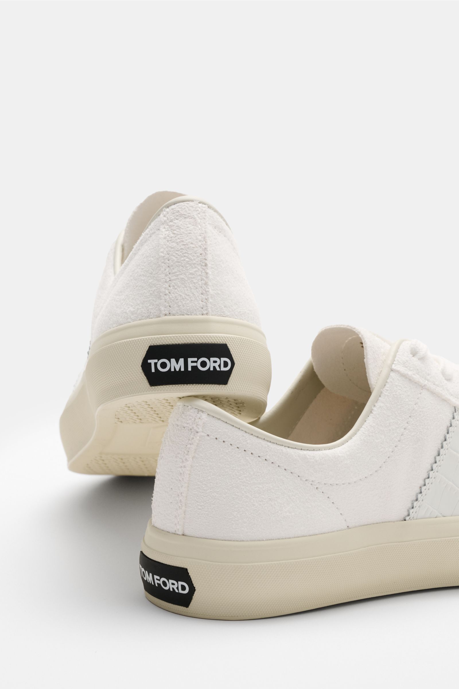 Rear angled view of Tom Ford Sneaker offwhite in premium suede and smooth leather overlays, featuring round toe, seven-eyelet lacing, leather lining, and rubber sole with TOM FORD logo.

Description: Cooler Luxus-Sneaker von TOM FORD: Das in Italien ge