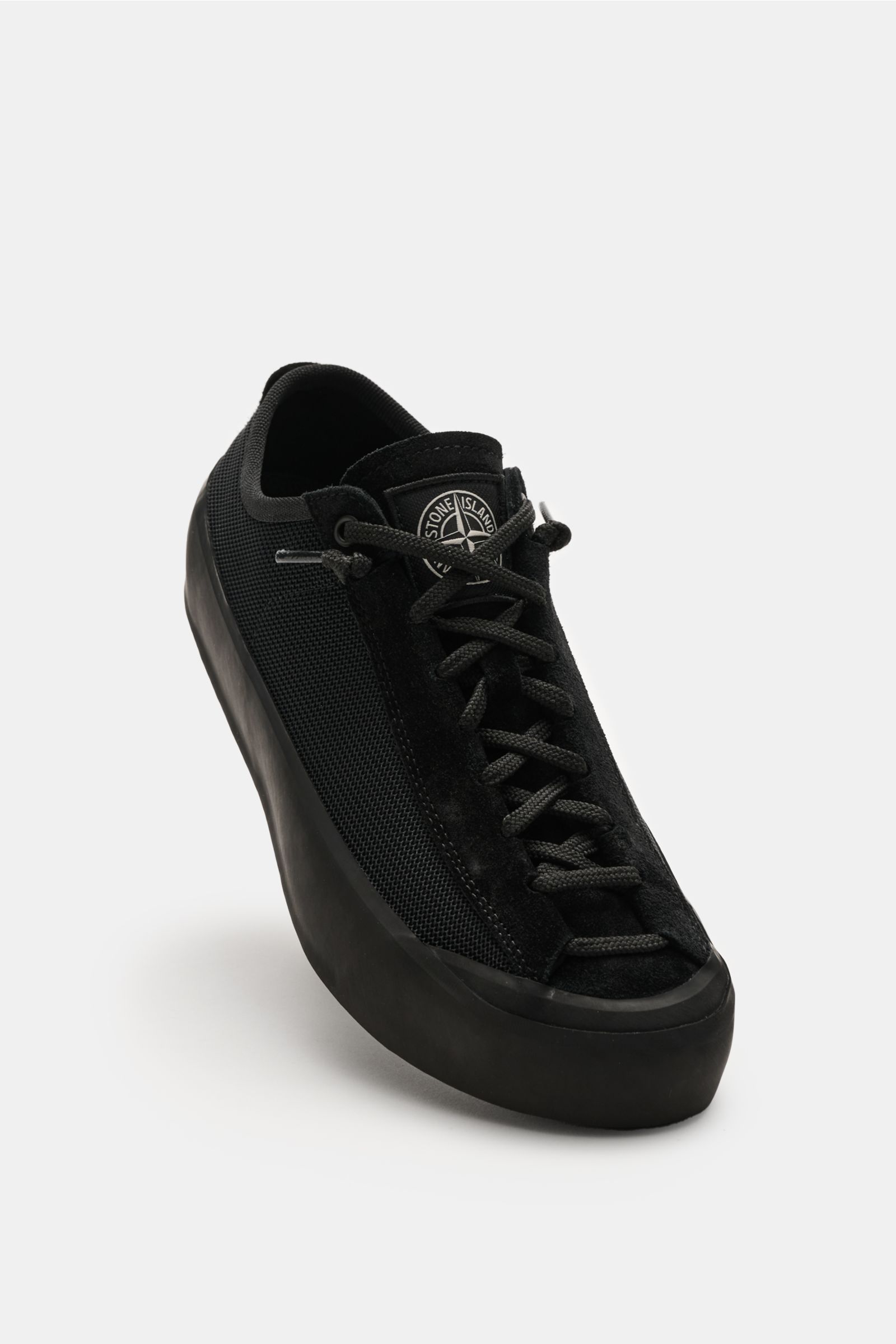 Stone Island Sneaker schwarz aus Veloursleder, Mesh und Gummi, runde Vorderkappe, sieben-Loch-Schnürung, robuste Gummisohle, frontal schräg fotografiert.
