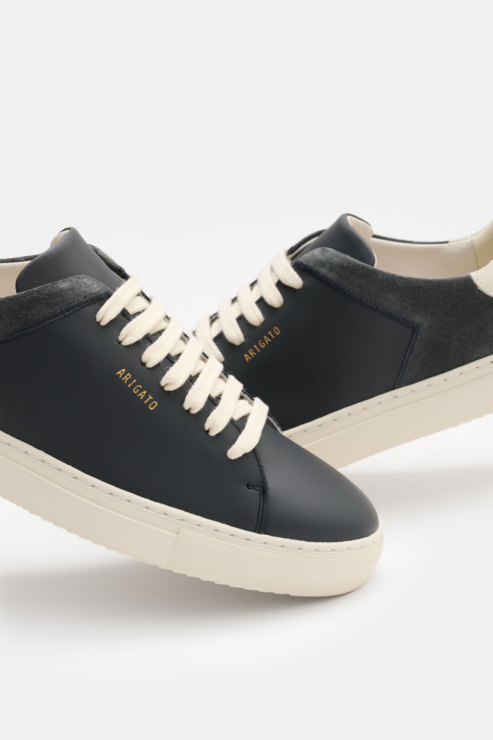 Axel Arigato Sneaker 'Clean 90 split' schwarz/offwhite, seitlich frontal fotografiert, Mix aus Glatt- und Veloursleder, runde Kappe, sieben-Loch-Schnürung, goldfarbene Prägung, gepolsterter Schaftrand, Lederfutter, flexible Gummisohle.