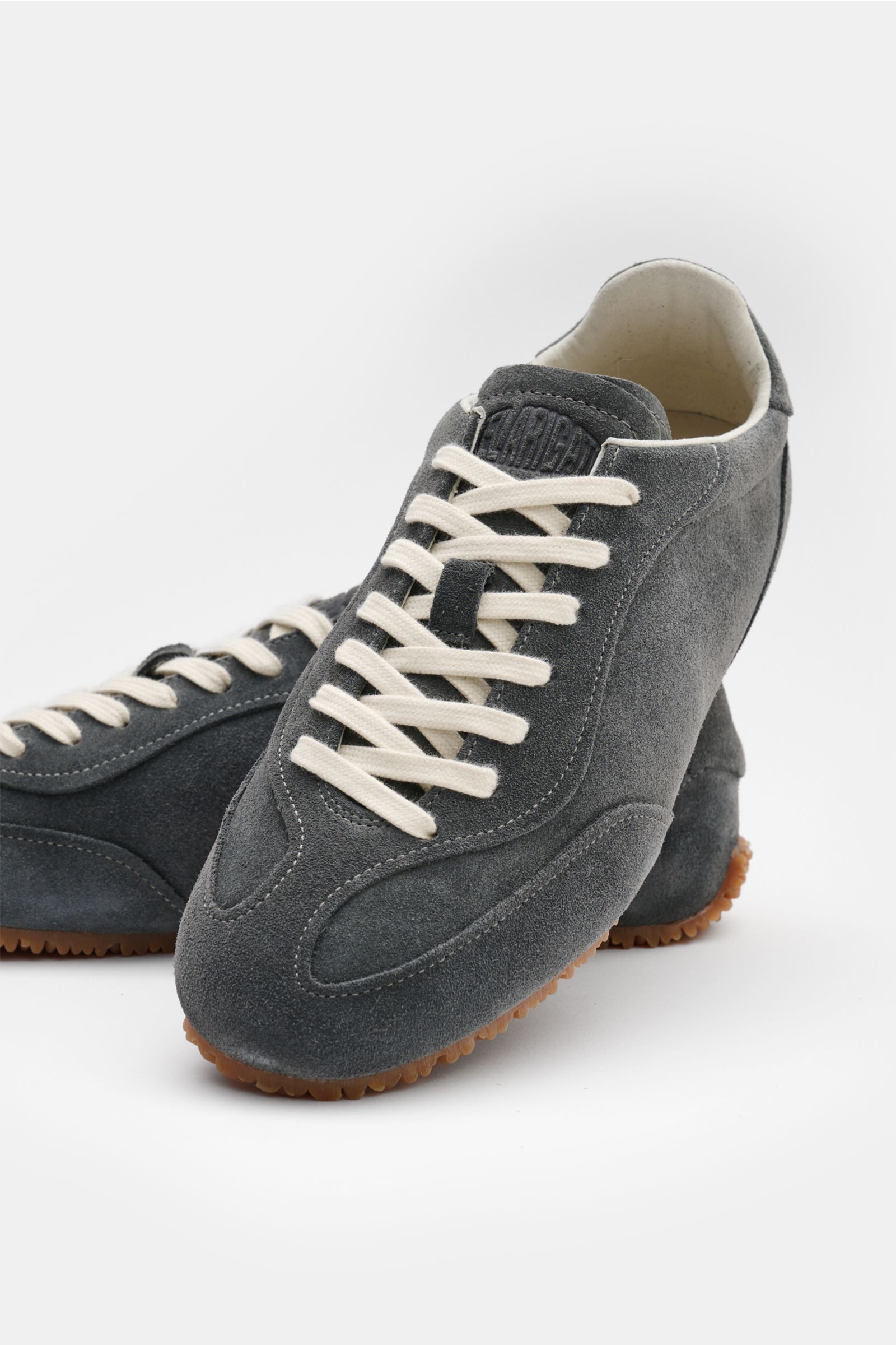 Axel Arigato Sneaker 'Daze Runner' dunkelgrau aus Veloursleder, seitlich vorne fotografiert, mit tonalen Overlays, weißer Schnürung.