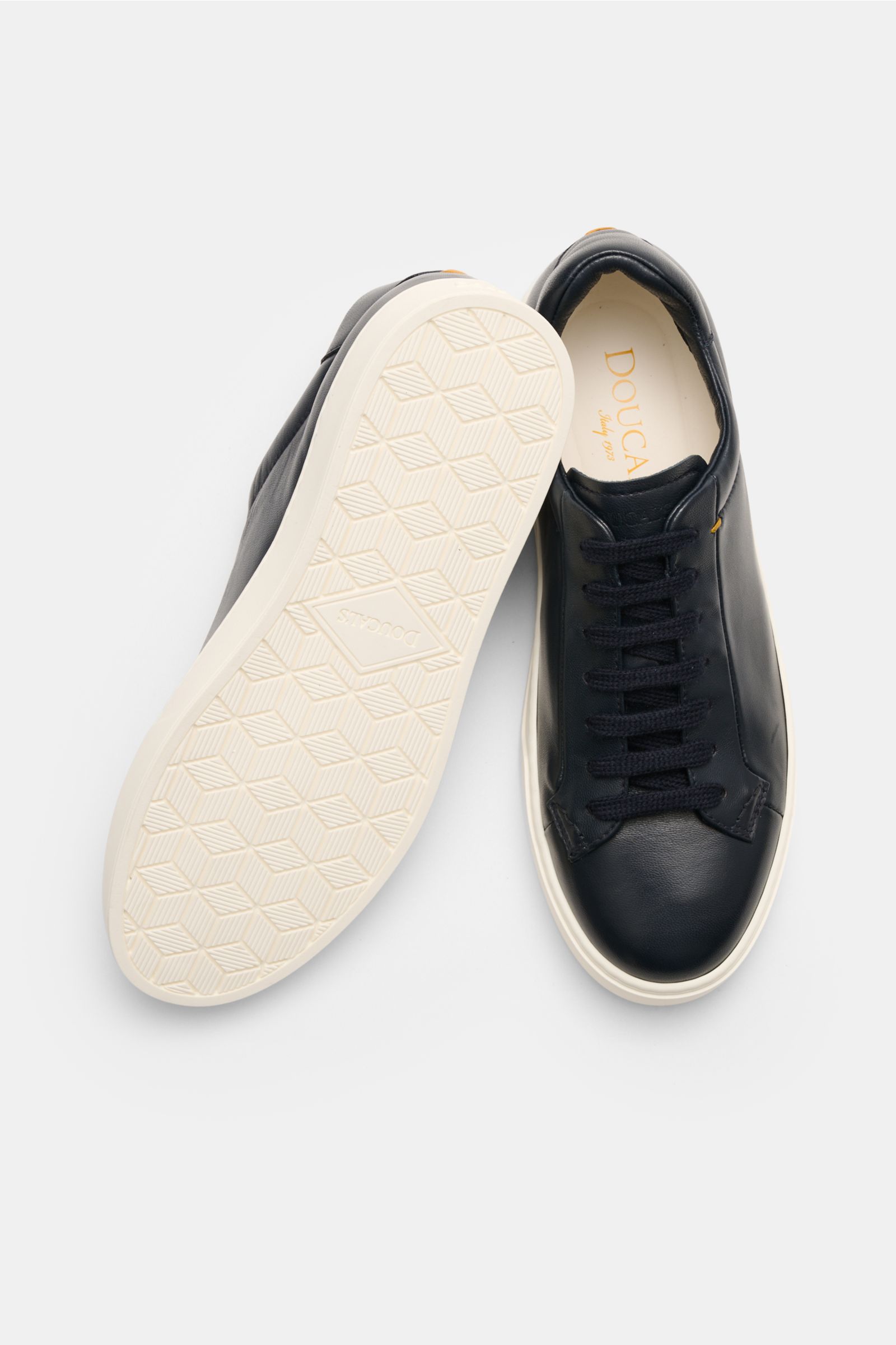 Doucal's Sneakers 'Plonge' dark navy shown from above with one shoe sole up, low top smooth leather, seven-eyelet lacing, padded topline, leather lining, flexible rubber sole.