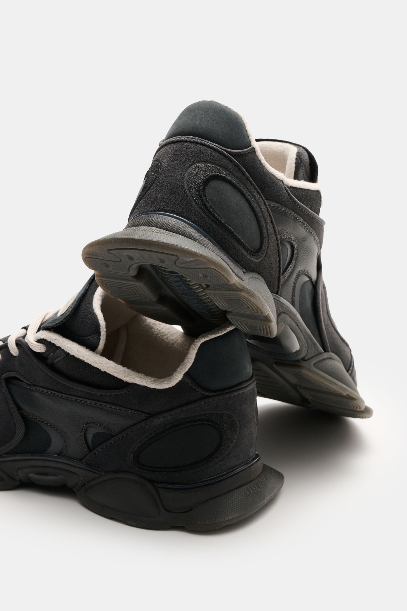 Rear and side view of Axel Arigato Sneaker 'Eris' schwarz in black with noble suede, smooth leather overlays, narrow silhouette, four-eyelet lacing, logo patch on tongue, textile lining, and rubber sole, photographed from a low angle.