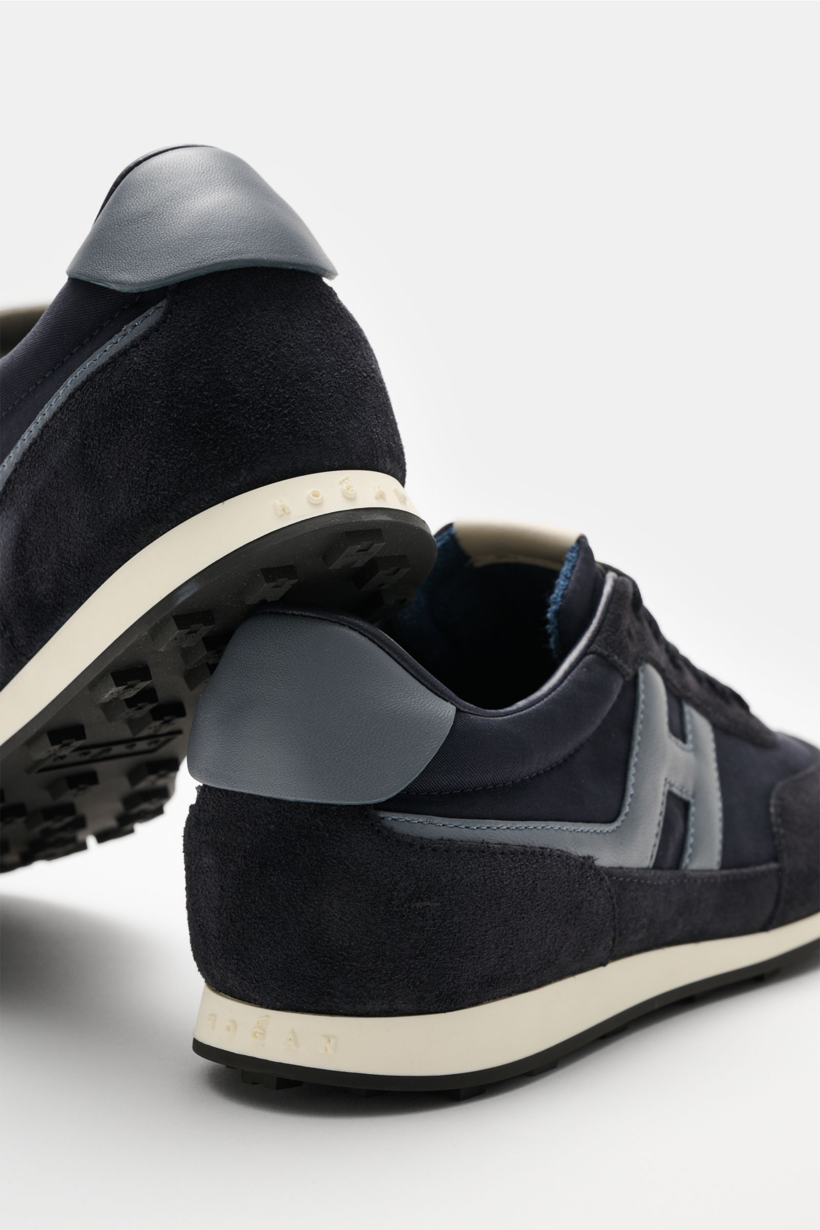 Close-up rear-side view of the Hogan Sneaker 'Allacciato' navy/rauchblau showing velours and smooth leather, contrasting overlays, 7-hole lacing, padded collar, leather-textile lining, memory foam footbed, and rubber sole with lug profile. Gehen wie au