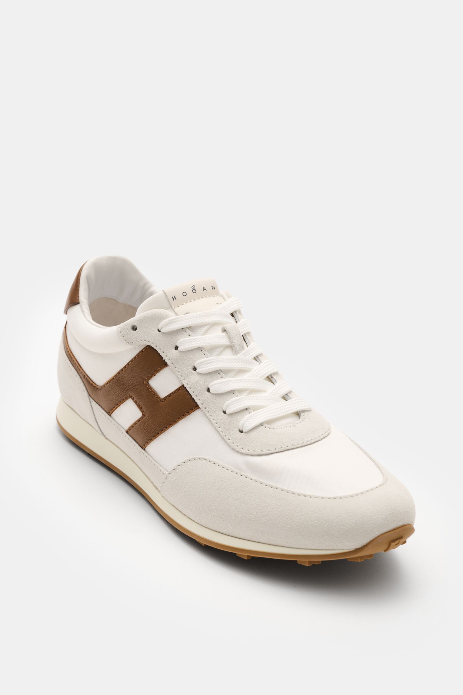 Hogan Sneaker 'Allacciato' braun/hellgrau shown from front-side angle, featuring velours and smooth leather, brown overlays, narrow silhouette, 7-hole lacing, padded collar, leather/textile lining, memory foam insole, and rubber sole with studded profile.