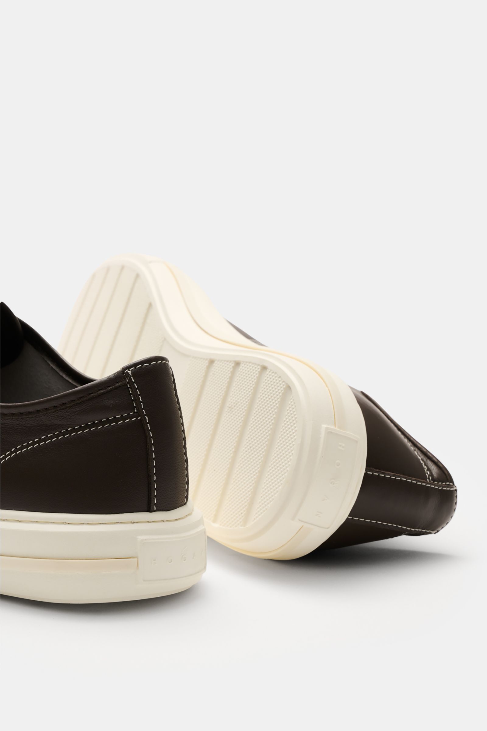 Hogan Sneaker 'Allacciato Cuciture' dunkelbraun/offwhite shown from rear and side angles, featuring smooth leather, seven-hole lacing, logo-printed tongue, H-shaped brand initial, leather and textile lining, memory foam footbed, and flexible rubber sole. 