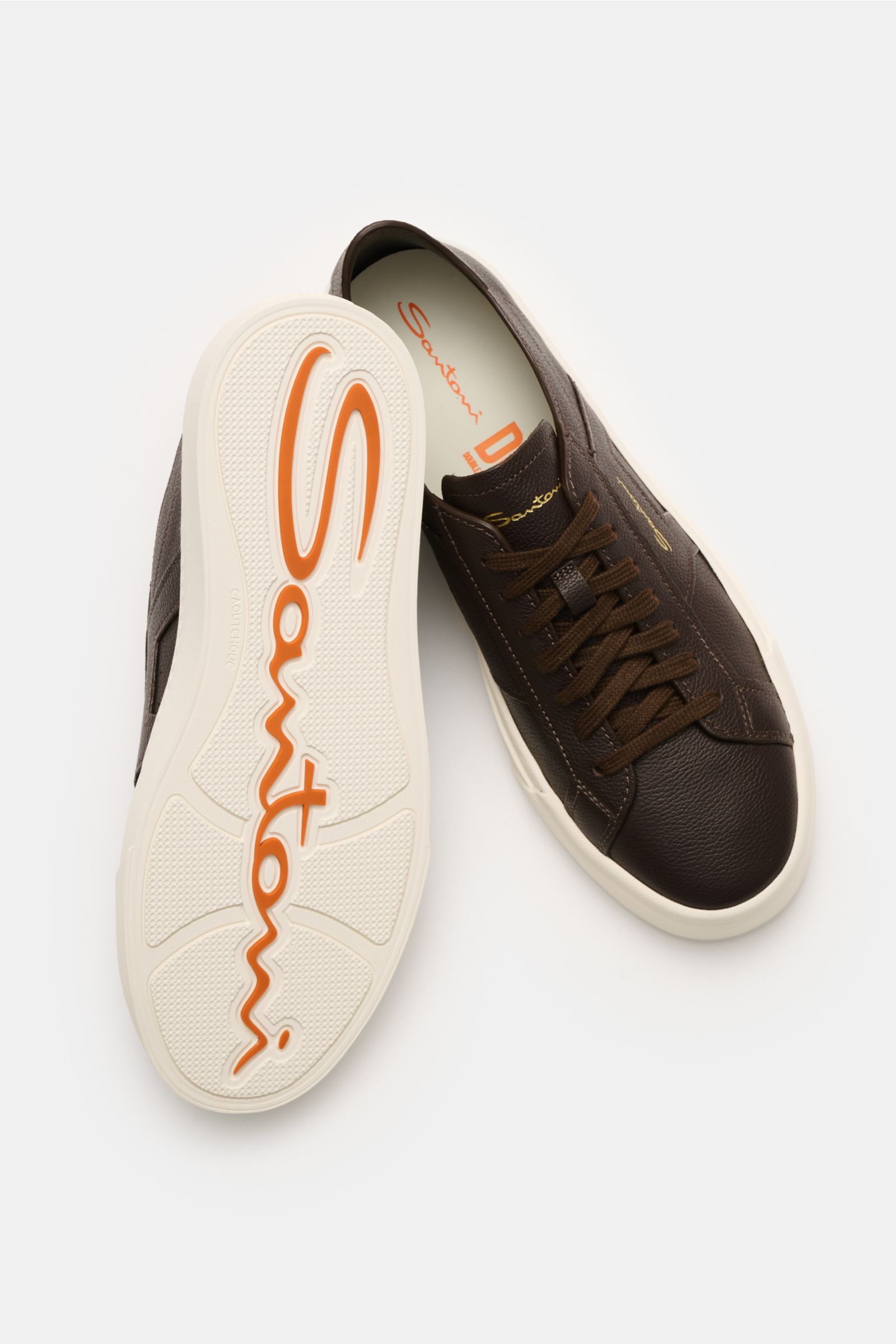 Top view of Santoni Sneaker 'Double Buckle' dunkelbraun in dark brown fine-grain leather with seven-hole lacing, double buckle overlay, padded collar, leather lining, and flexible rubber sole showing orange Santoni logo. Hommage an einen Klassiker: Die Ov