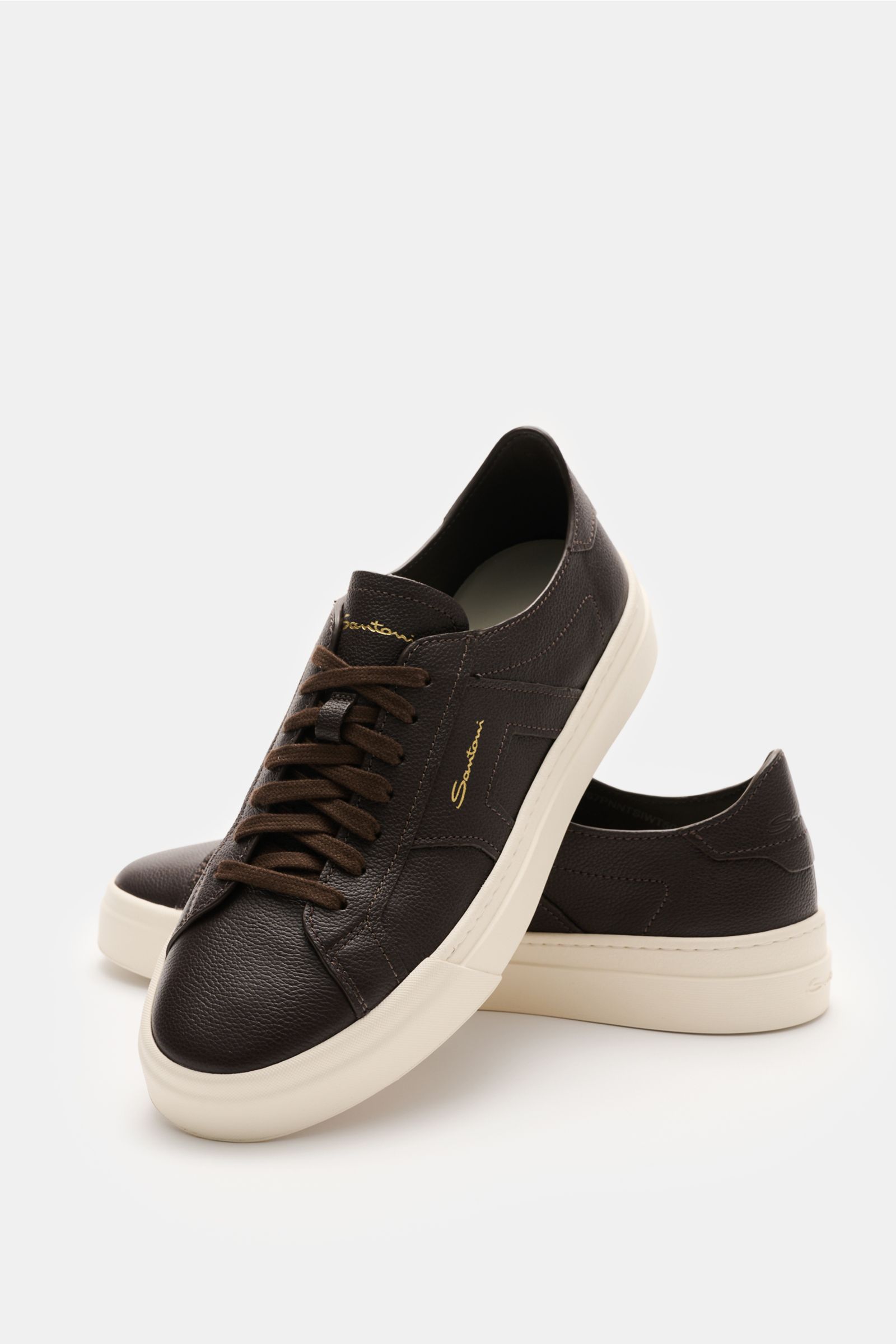 Santoni Sneaker 'Double Buckle' dunkelbraun shown from a front-side angle, made of finely grained leather with signature double buckle overlays, round shape, seven-eyelet lacing, emblem on the tongue, padded collar, leather lining, and flexible rubber sol