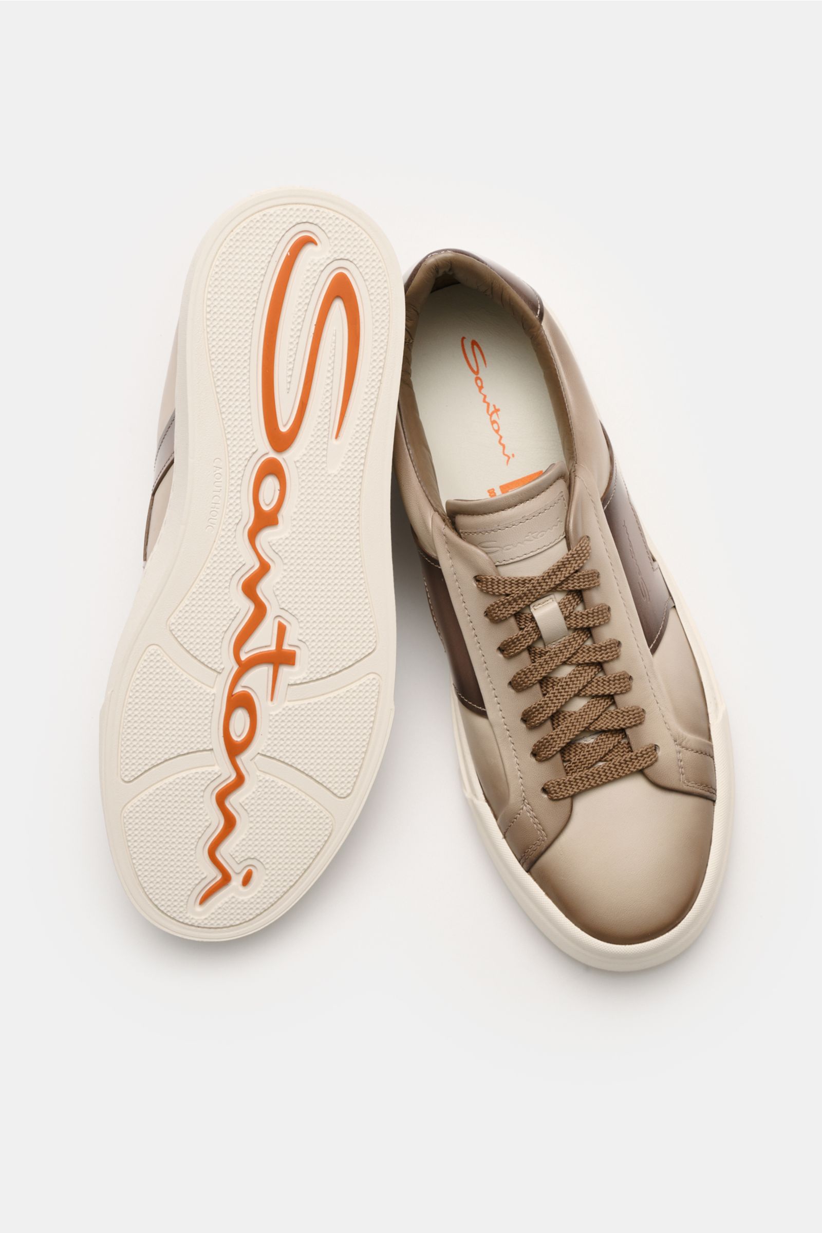 Santoni Sneaker 'Double Buckle' taupe shown from above with one shoe sole up, featuring fine leather, double buckle overlay, round shape, seven-eyelet lacing, emblem on tongue, padded collar, leather lining, flexible rubber sole; homage to classic monkstr