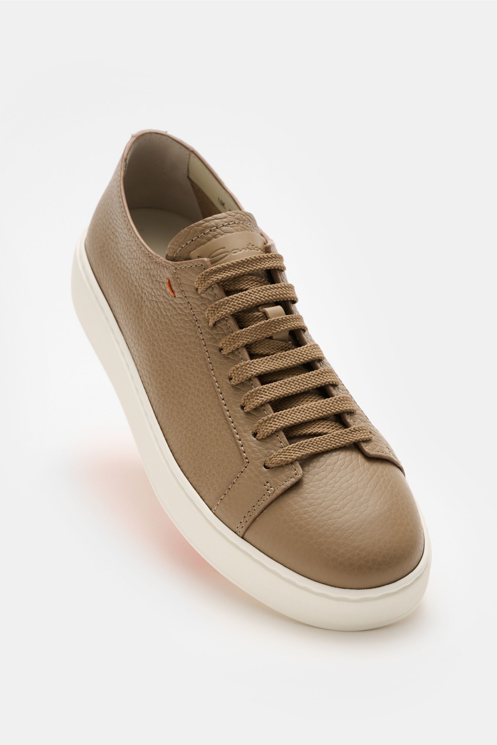 Santoni Sneaker 'Clean Icon' taupe shown from a front-side angle, featuring markant genarbtes Glattleder, matte Optik, runde Vorderkappe, Sieben-Loch-Schnürung, dezentes kontrastfarbiges Stitching-Detail, Innenfutter aus Leder, and flexible Kautschuksohle