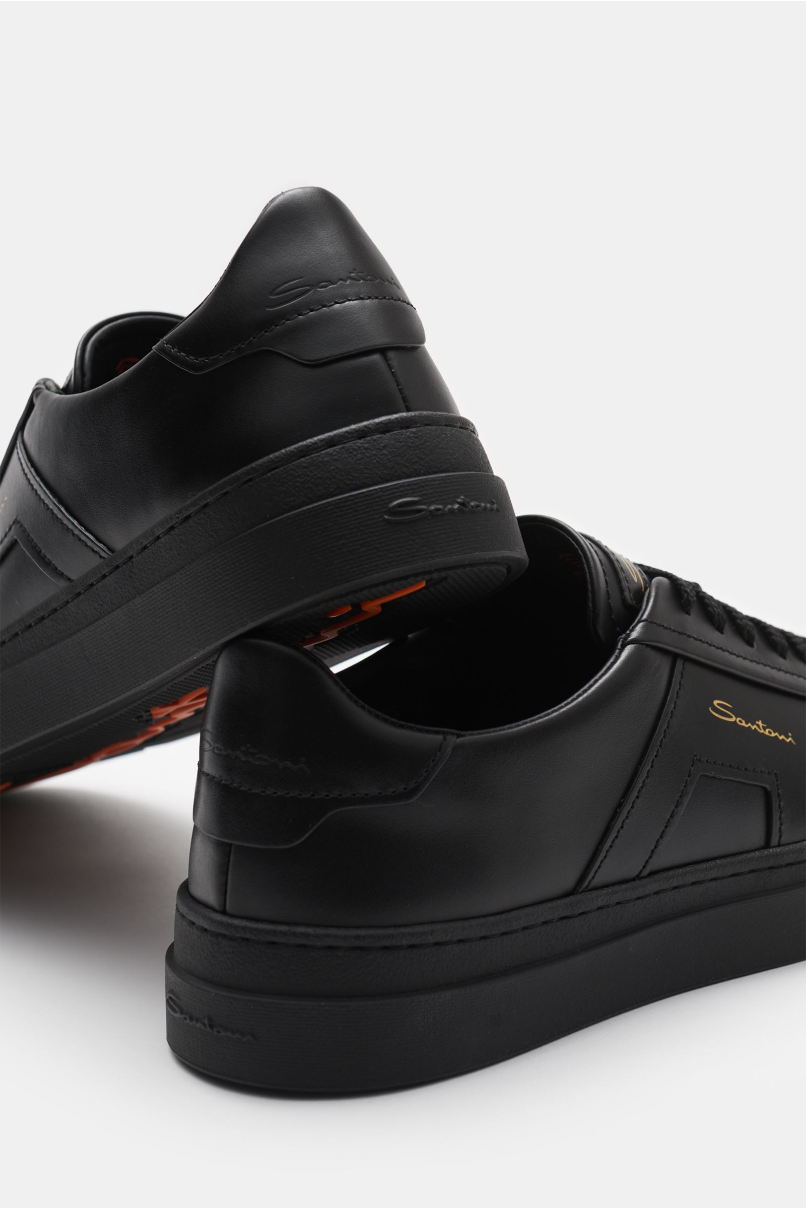 Rear and side view of Santoni Sneaker 'Double Buckle' schwarz in black smooth leather, featuring seven-hole lacing, rounded toe cap, tonal overlays and emblem, padded collar, leather lining, flexible rubber sole, and sole branding. Den klassischen Tenniss