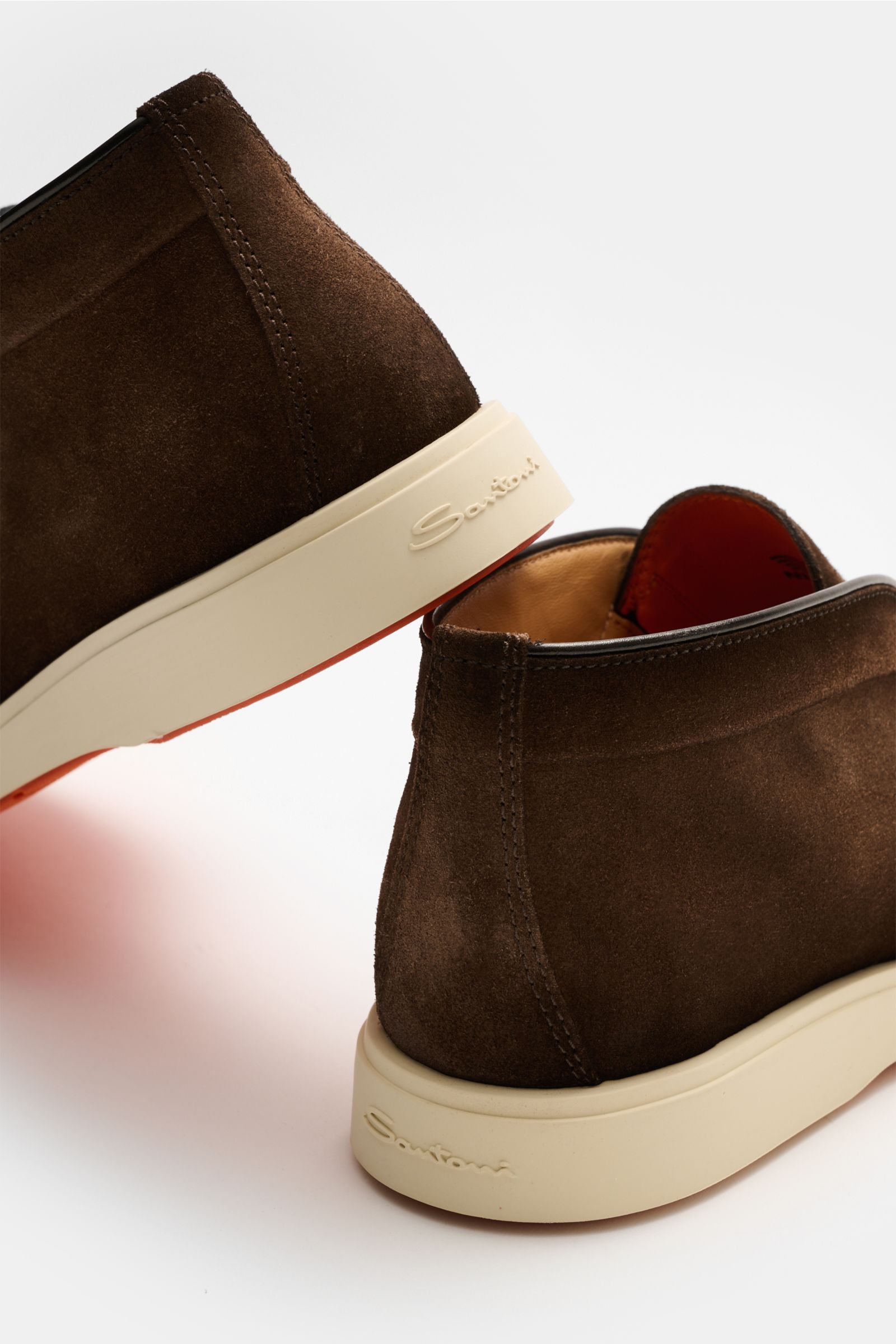 Rear and side view of Santoni Desert Boot 'Detroit' braun made of smooth brown suede with a flexible white rubber sole and leather lining.

Desert Boot aus geschmeidigem Veloursleder von SANTONI: Die flexible Gummisohle im Sneaker-Stil sorgt sowohl für