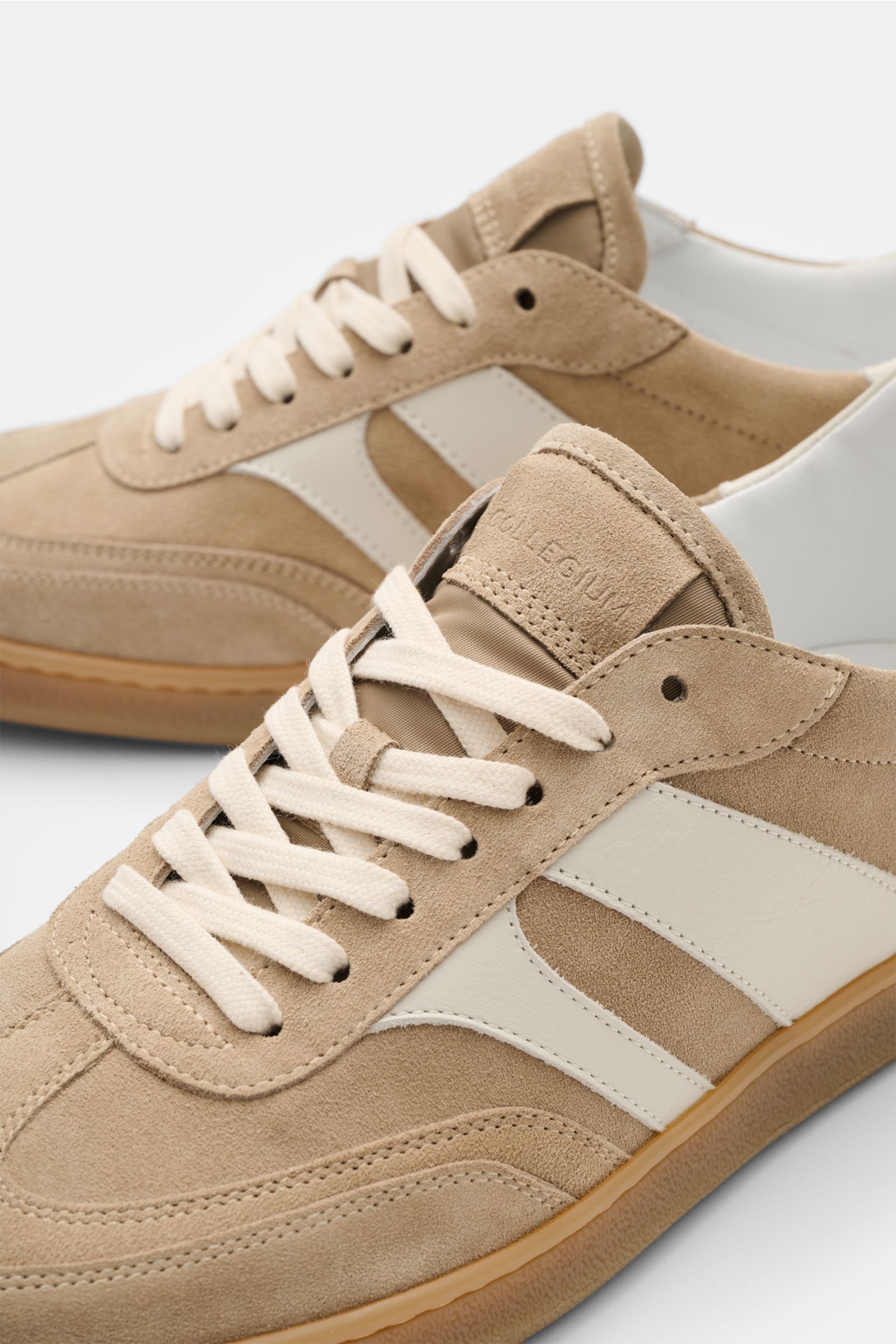 Close-up front-side perspective of Collegium Sneaker 'Pillar Court III' beige/offwhite in soft suede and smooth leather with seven-hole lacing, padded collar, leather lining, logo-embossed tongue, and flexible gum sole. 

Das amerikanische Label COLLEG
