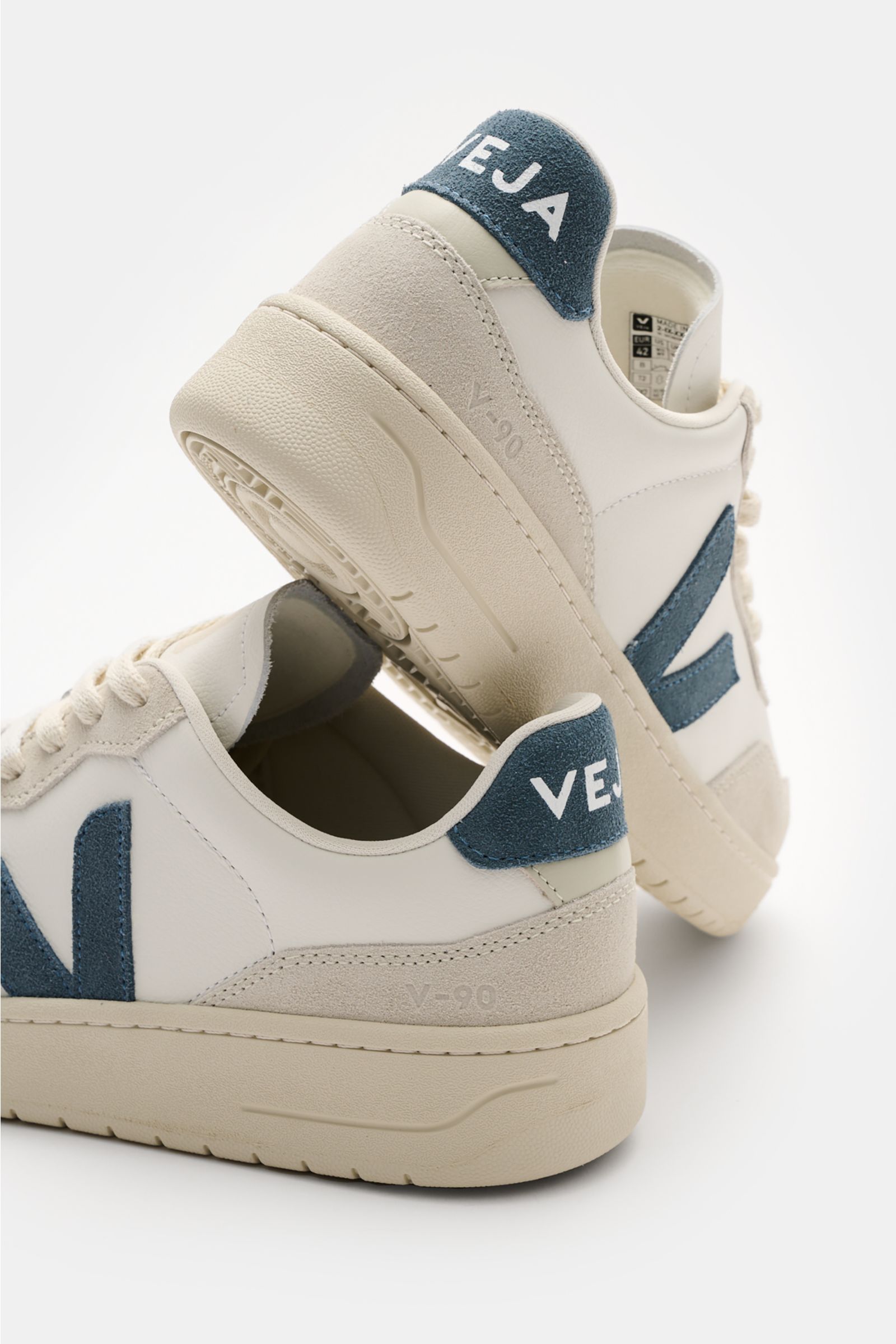 Rear and side view of Veja Sneaker 'V-90 O.T. Leather' offwhite/hellgrau/graublau made of sustainable leather with padded collar, tonal V-overlay, perforated round toe, seven-eye lacing, jersey lining, and recycled rubber sole.
