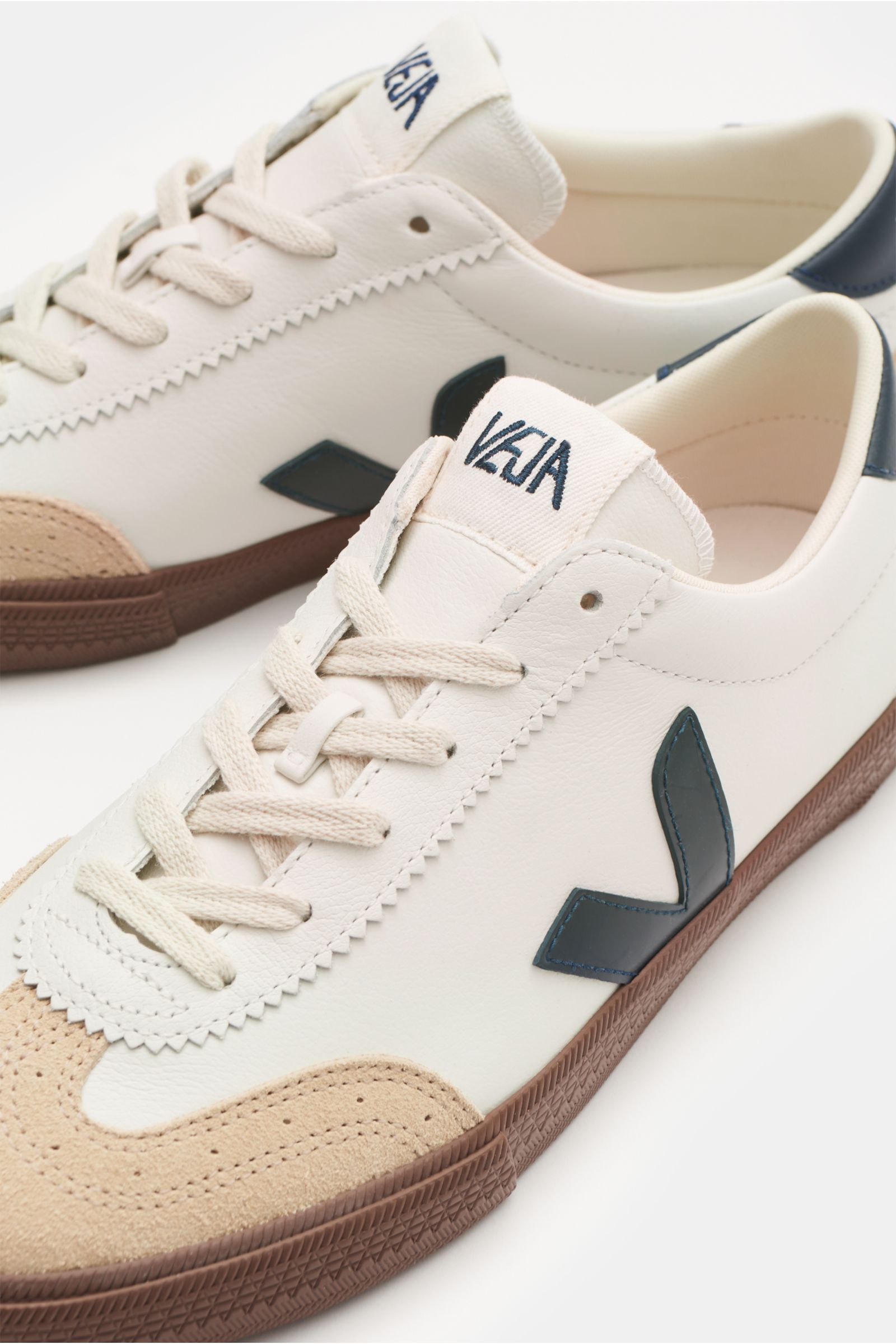 Veja Sneaker 'Volley O.T. Leather' weiß/navy/beige shown from a close-up side and top angle, featuring smooth Organic Traced leather, suede overlays, round toe, six-hole lacing, V-Overlay, padded collar with logo, textile lining, and flexible recycled rub