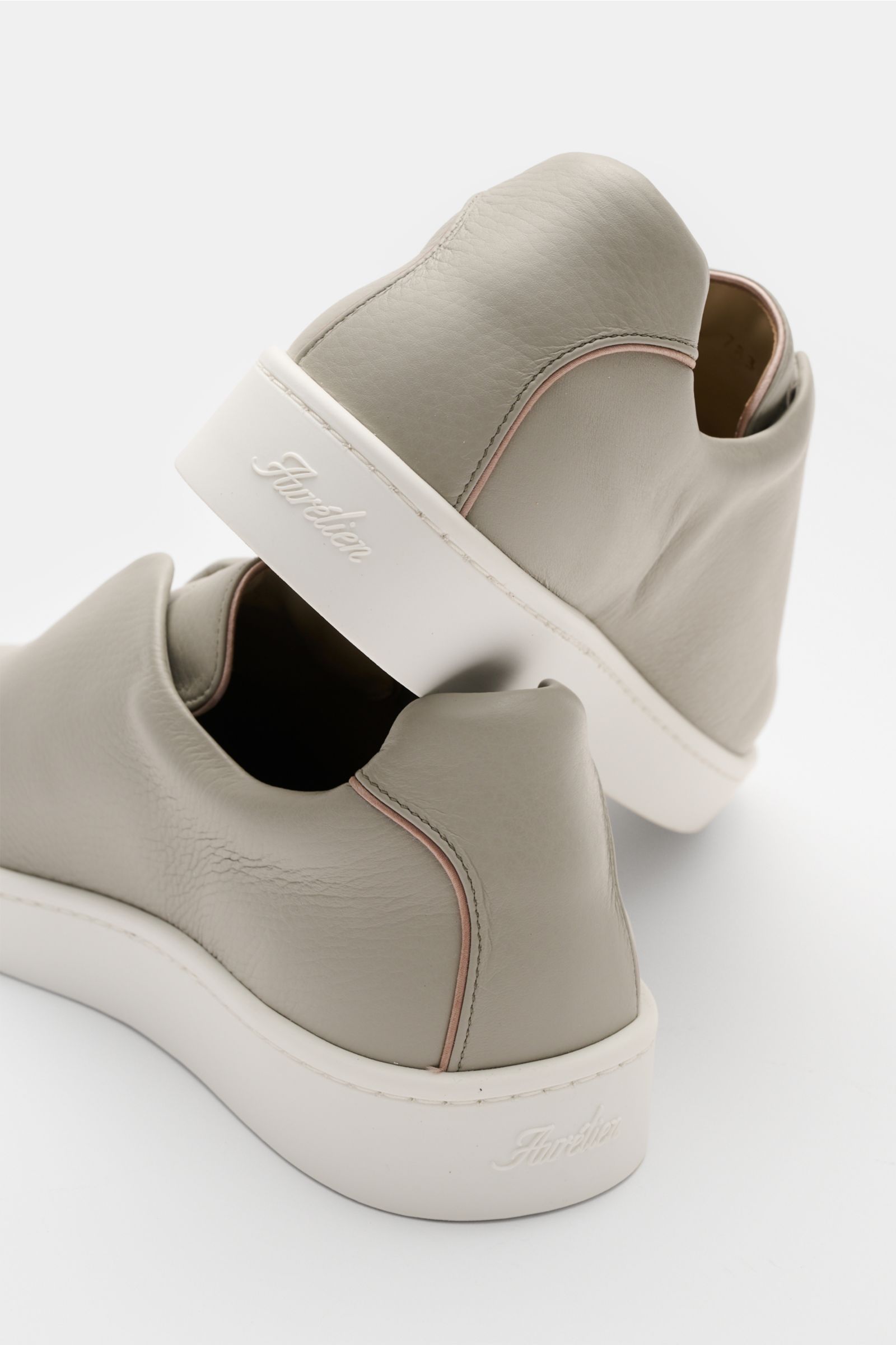 Aurélien Slip-on-Sneaker grau, seitlich hinten fotografiert, fein genarbtes Leder, runde Vorderkappe, elastische Bänder, gepolsterter Schaftrand, dezente Prägung, Lederfutter, flexible Gummisohle.