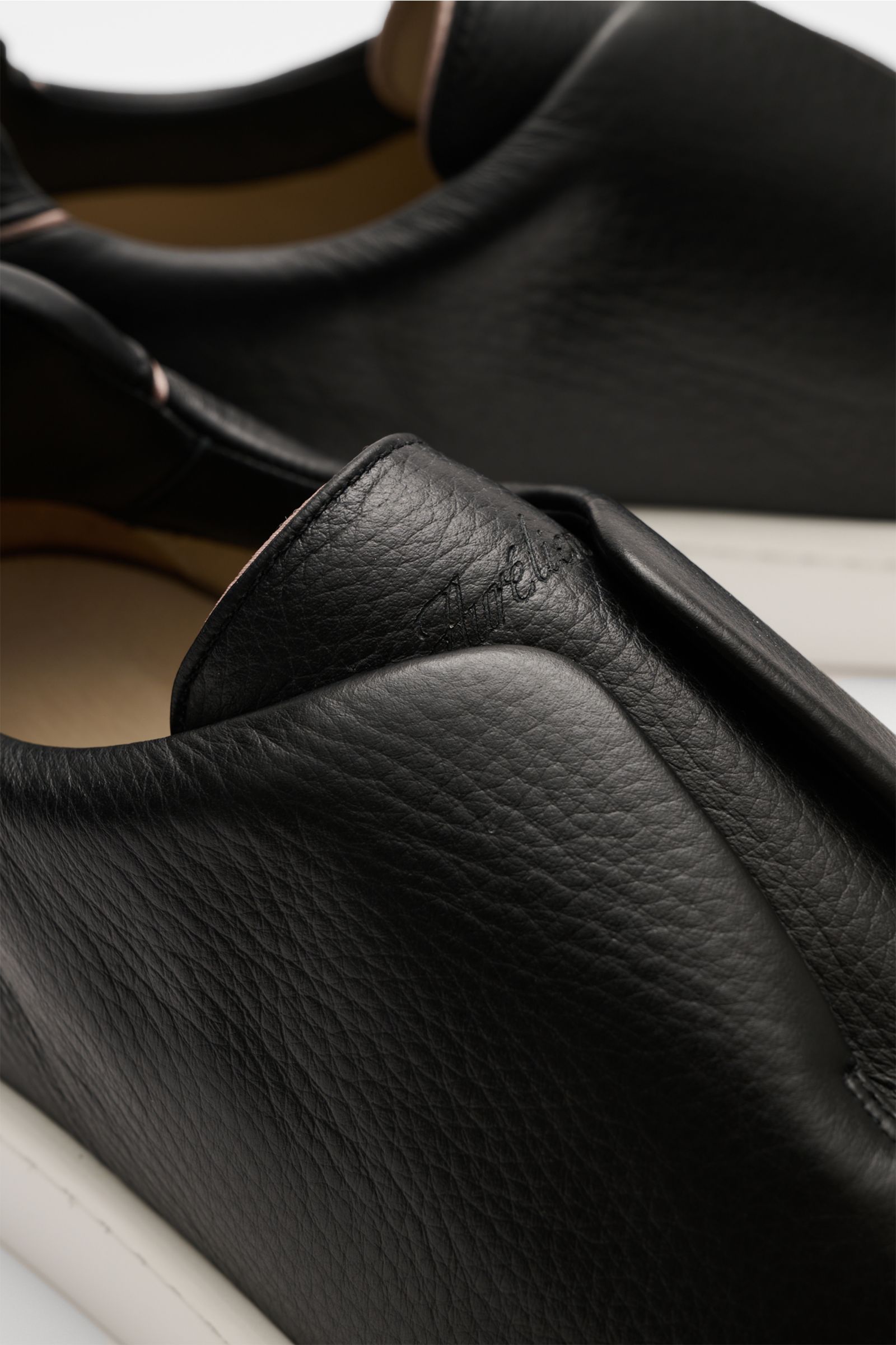 Nahaufnahme aus schräger Perspektive des Aurélien Slip-on-Sneaker schwarz mit fein genarbtem Leder, runder Vorderkappe, elastischen Bändern, gepolstertem Schaftrand, Lederfutter, dezenter Logo-Prägung und flexibler Gummisohle.