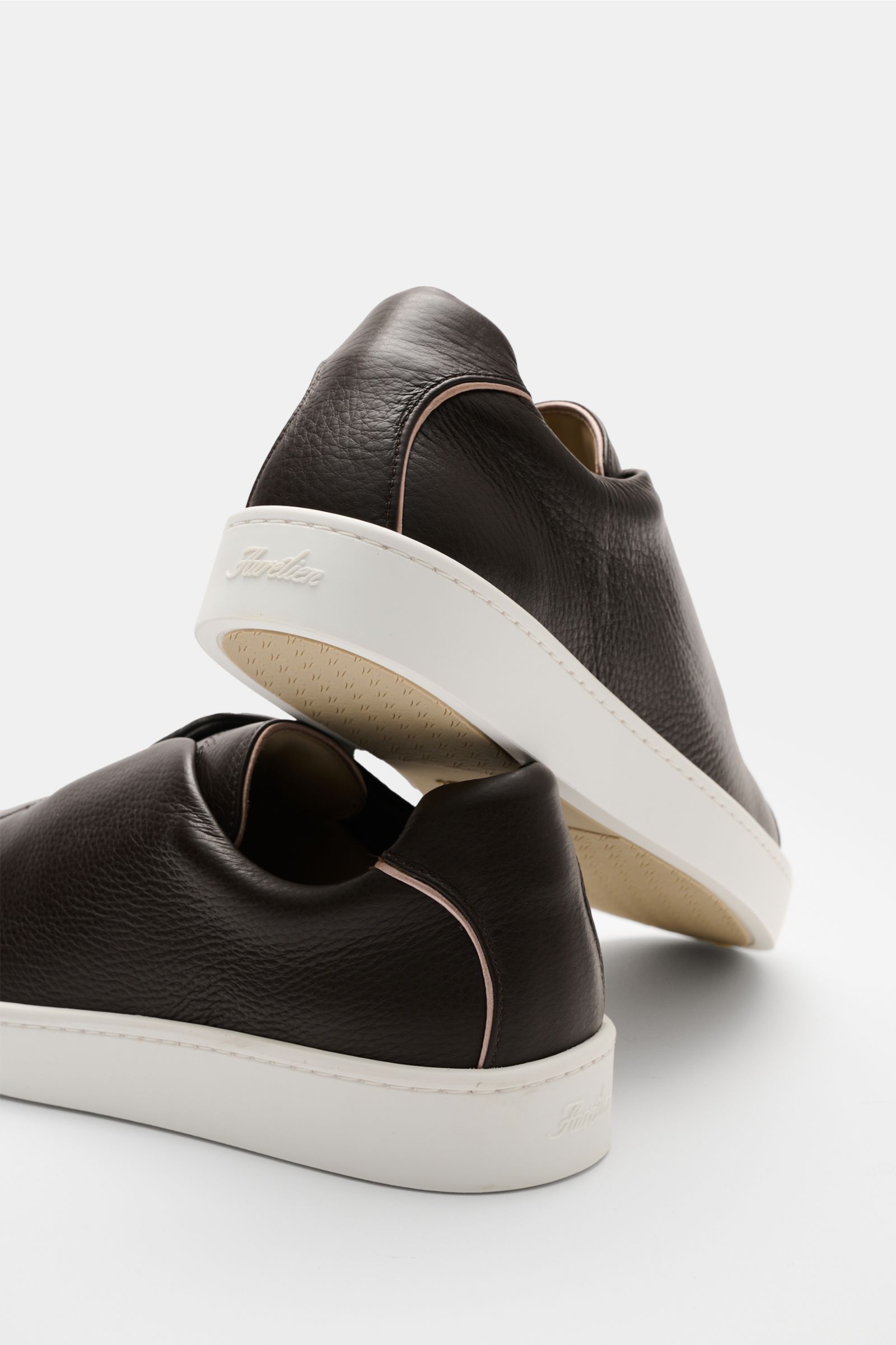 Aurélien Slip-on-Sneaker dunkelbraun aus fein genarbtem Leder mit runder Vorderkappe, elastischen Bändern, gepolstertem Schaftrand, Lederinnenfutter, flexibler Gummisohle, dezenter Logo-Prägung, Rückansicht schräg von hinten.