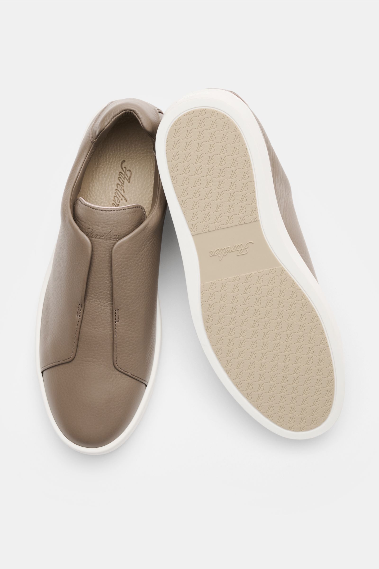 Aurélien Slip-on-Sneaker taupe aus fein genarbtem Leder, schnürsenkellos mit runder Vorderkappe, elastischen Bändern, Lederfutter, Gummisohle, schräg von oben fotografiert.