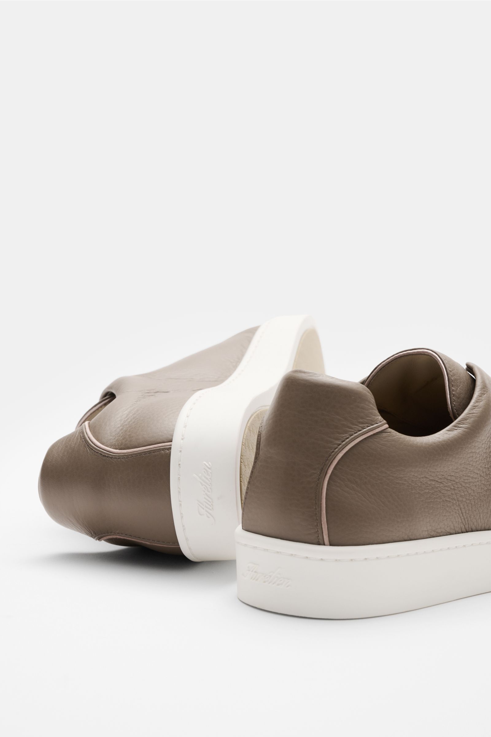Aurélien Slip-on-Sneaker taupe in seitlicher Nahaufnahme, fein genarbtes Leder, runde Vorderkappe, elastische Bänder, gepolsterter Schaftrand, flexible weiße Gummisohle.
