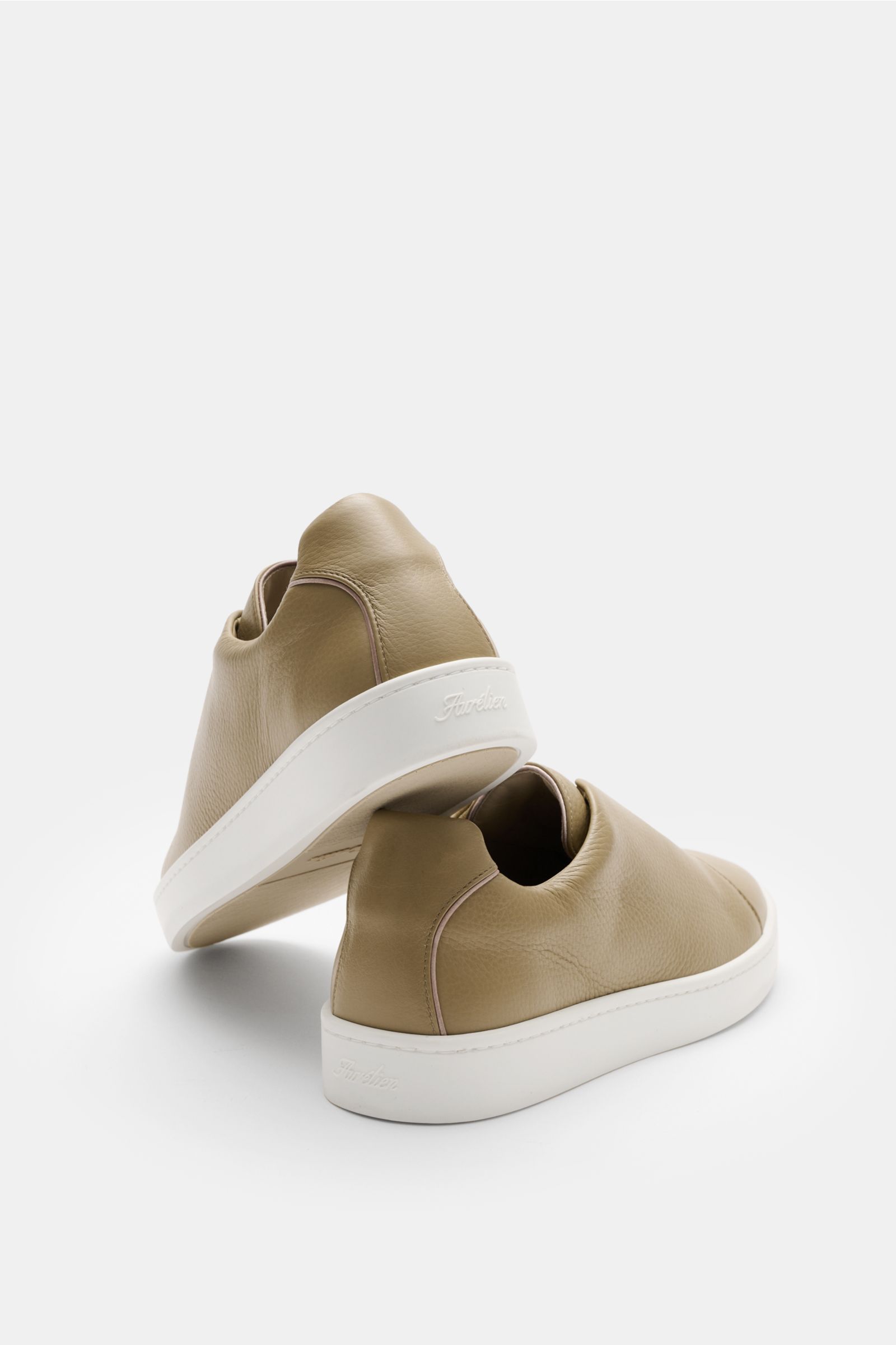 Aurélien Slip-on-Sneaker hellbraun, seitlich von hinten fotografiert, fein genarbtes Leder, runde Vorderkappe, elastische Bänder, gepolsterter Schaftrand, dezente Logo-Prägung, flexible weiße Gummisohle.