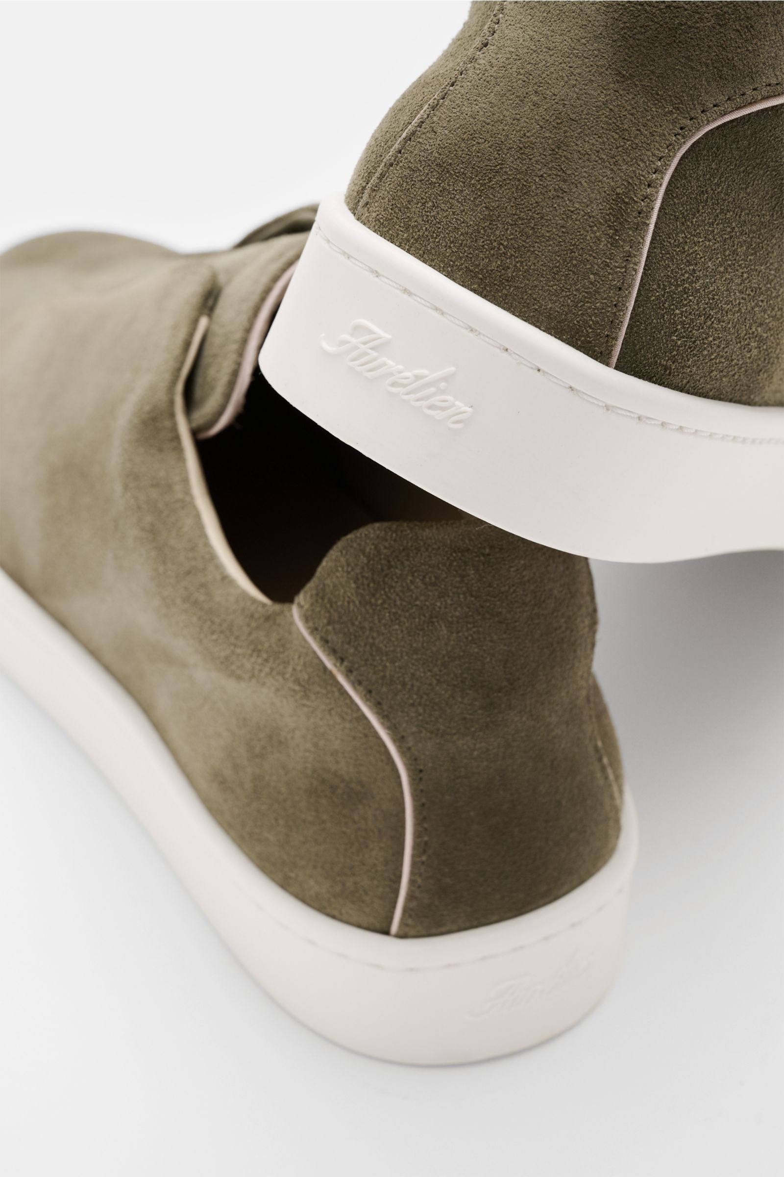 Aurélien Slip-on-Sneaker oliv aus softem Veloursleder, flexible Gummisohle, runde Vorderkappe, gepolsterter Schaftrand, seitliche Elastikbänder, Ansicht von hinten schräg oben.