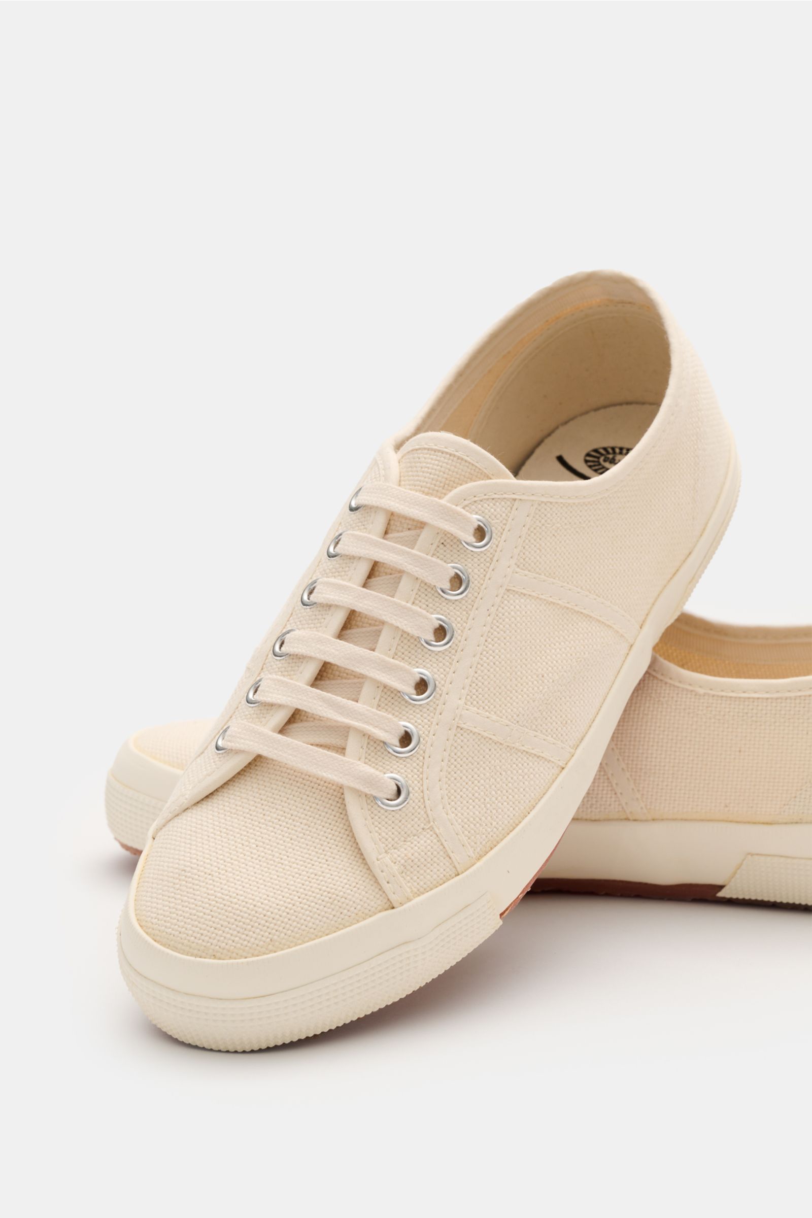 Superga Sneaker 'Cotu Classic' creme/offwhite im Detail, von schräg vorne fotografiert, robustes Canvas, sechs-Loch-Schnürung, Baumwoll-Innenfutter, flexible Gummisohle.