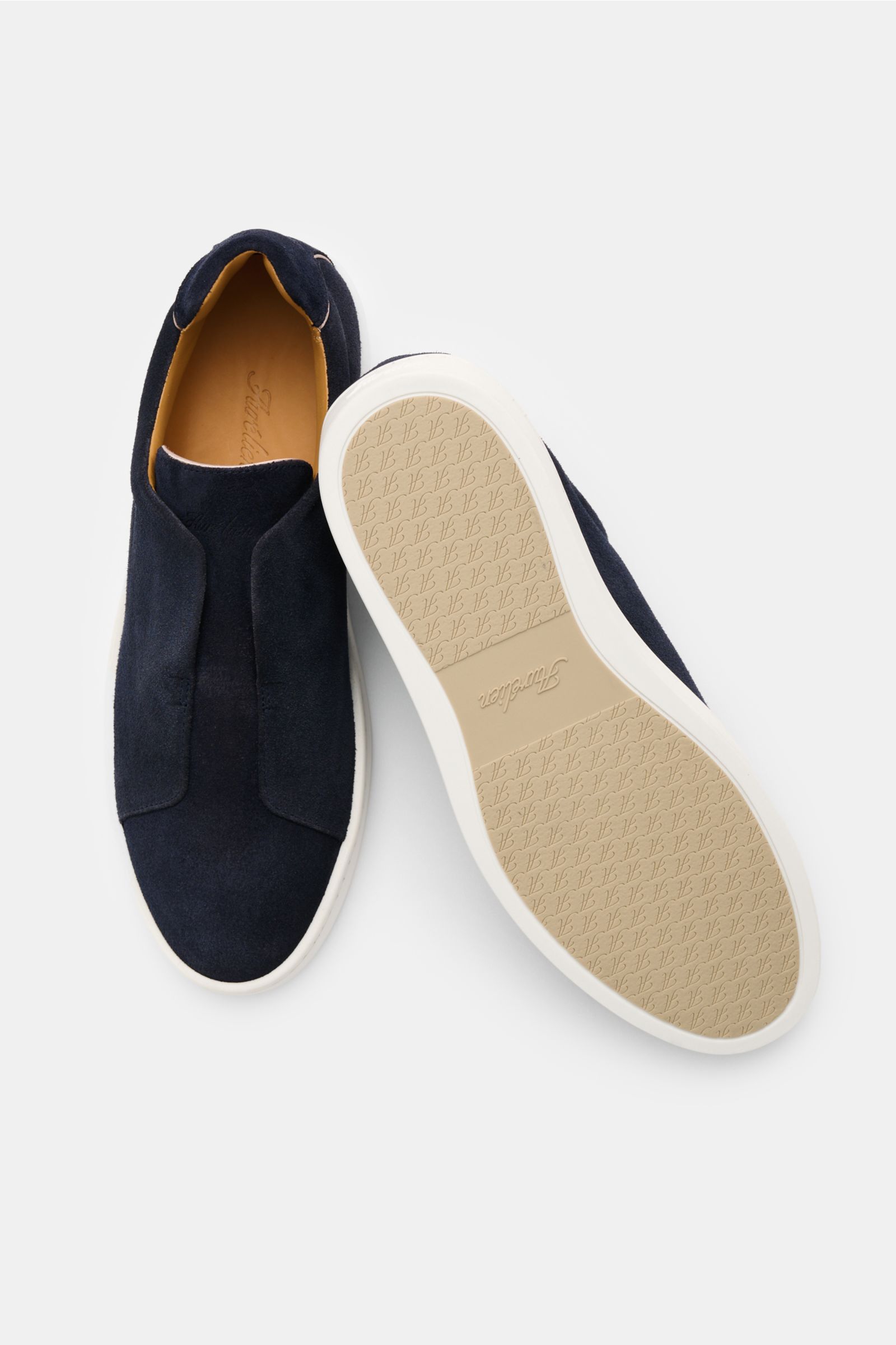 Aurélien Slip-on-Sneaker navy shown from top and sole view, made of soft velour leather with rounded toe, elastic bands inside, padded collar, subtle logo embossing, leather lining, and flexible rubber sole. Reinschlüpfen und loslaufen – nichts trifft bes