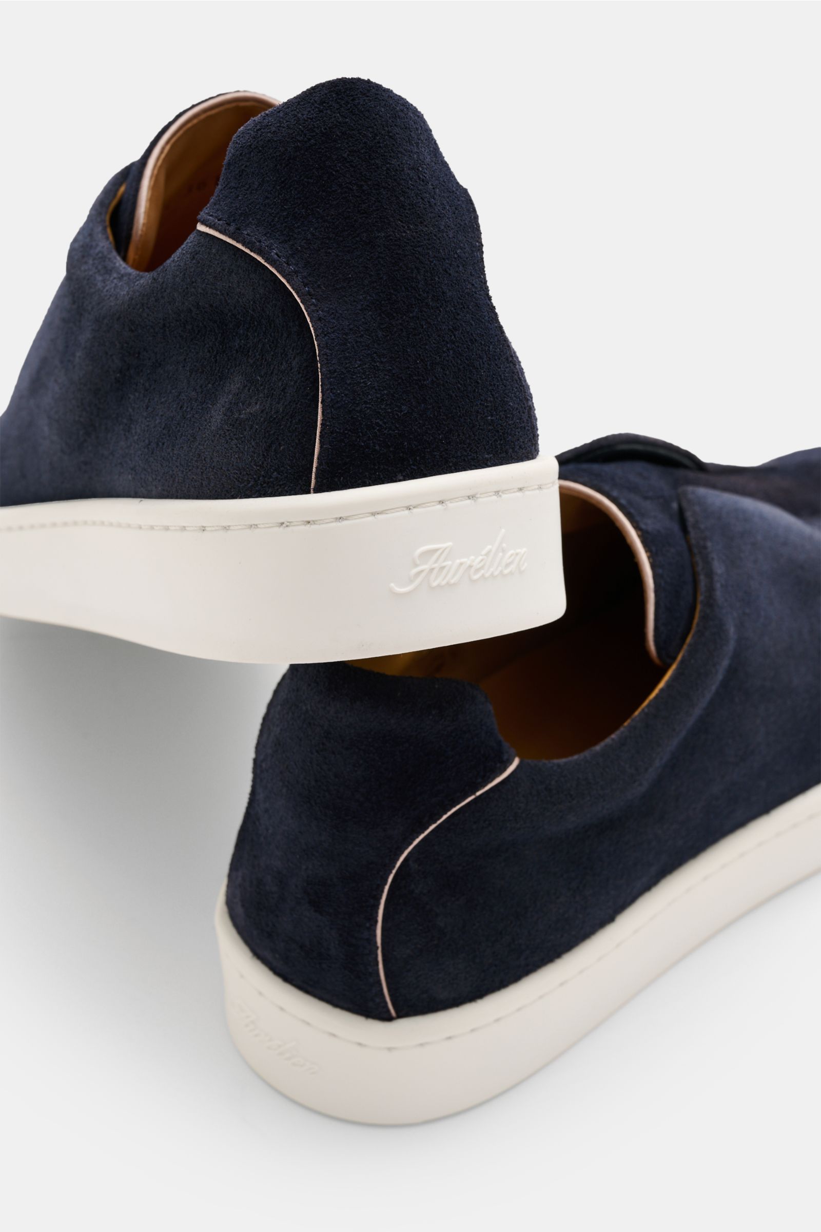 Rear side view of Aurélien Slip-on-Sneaker navy in soft navy suede with white flexible rubber sole, round toe, elastic bands, padded collar, leather lining, and subtle logo embossing.