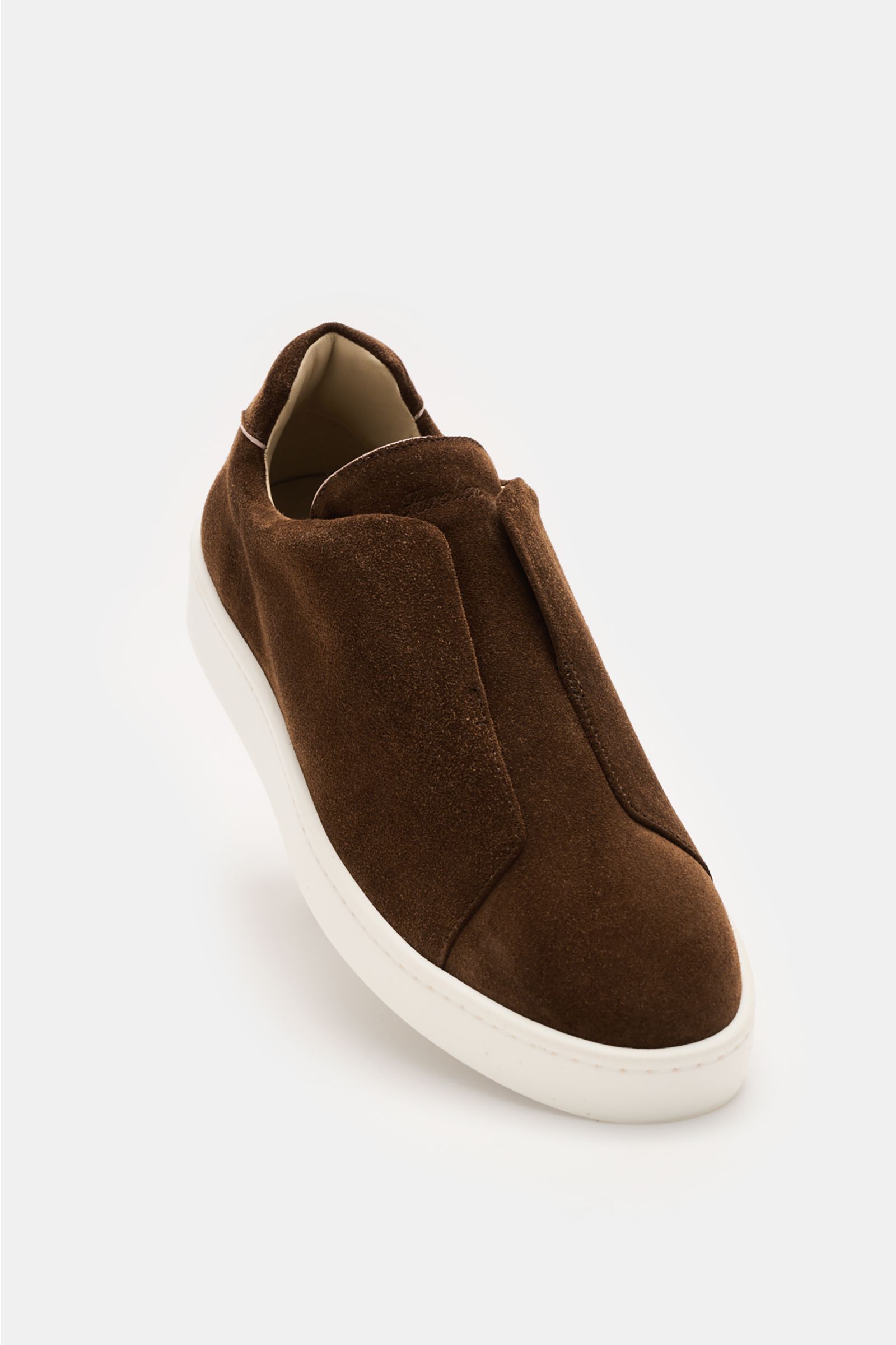Aurélien Slip-on-Sneaker braun aus softem Veloursleder, runder Vorderkappe, elastischen Bändern, gepolstertem Schaftrand und flexibler weißer Sohle, frontale Perspektive.