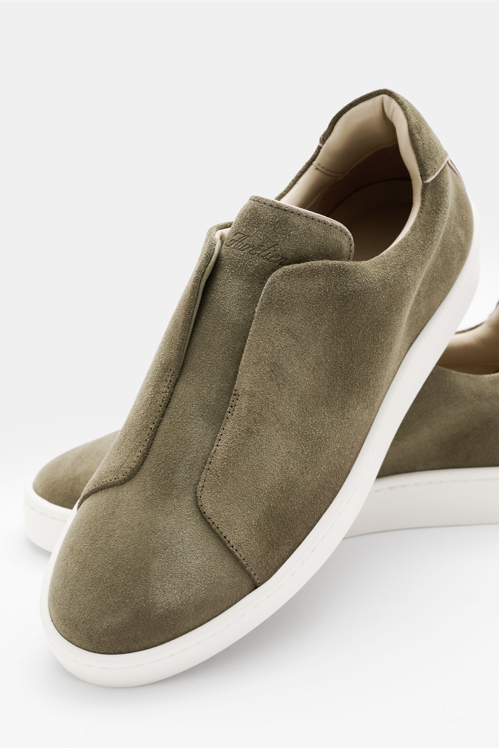 Front angled view of Aurélien Slip-on-Sneaker oliv in soft olive velour leather with rounded toe, elastic bands, padded collar, and white flexible sole.

Description: Reinschlüpfen und loslaufen – nichts trifft besser auf den puristischen Slip-on-Sneak