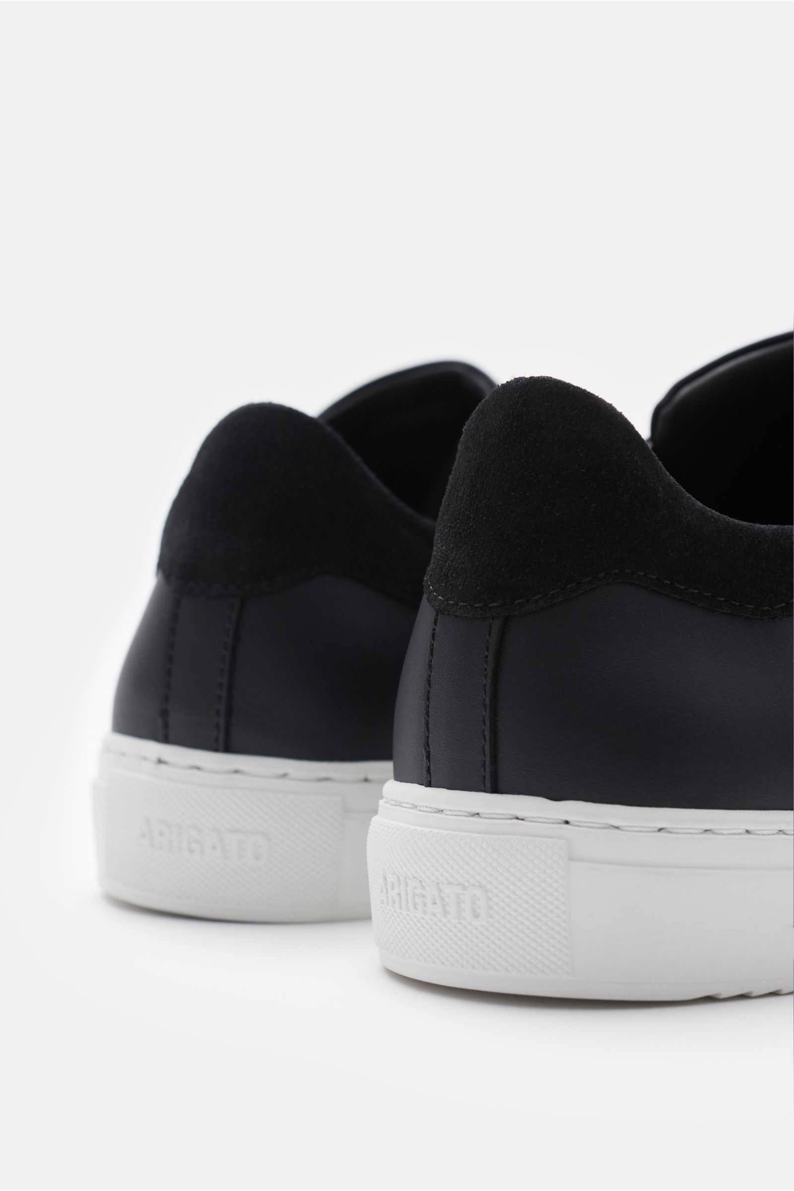 Axel Arigato Sneaker 'Clean 90' schwarz, Detailaufnahme von hinten mit Glattleder, Veloursleder-Detail, gepolstertem Schaftrand, weißer Gummisohle.