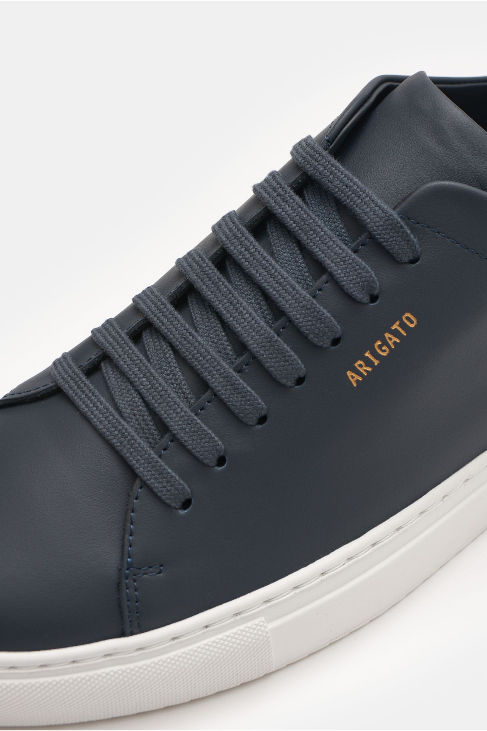 Nahaufnahme von Axel Arigato Sneaker 'Clean 90' navy aus seitlicher Perspektive mit Glattleder, Veloursleder-Detail, runder Vorderkappe, Sieben-Loch-Schnürung, goldfarbener Prägung, gepolstertem Schaftrand, Lederinnenfutter und flexibler Gummisohle.