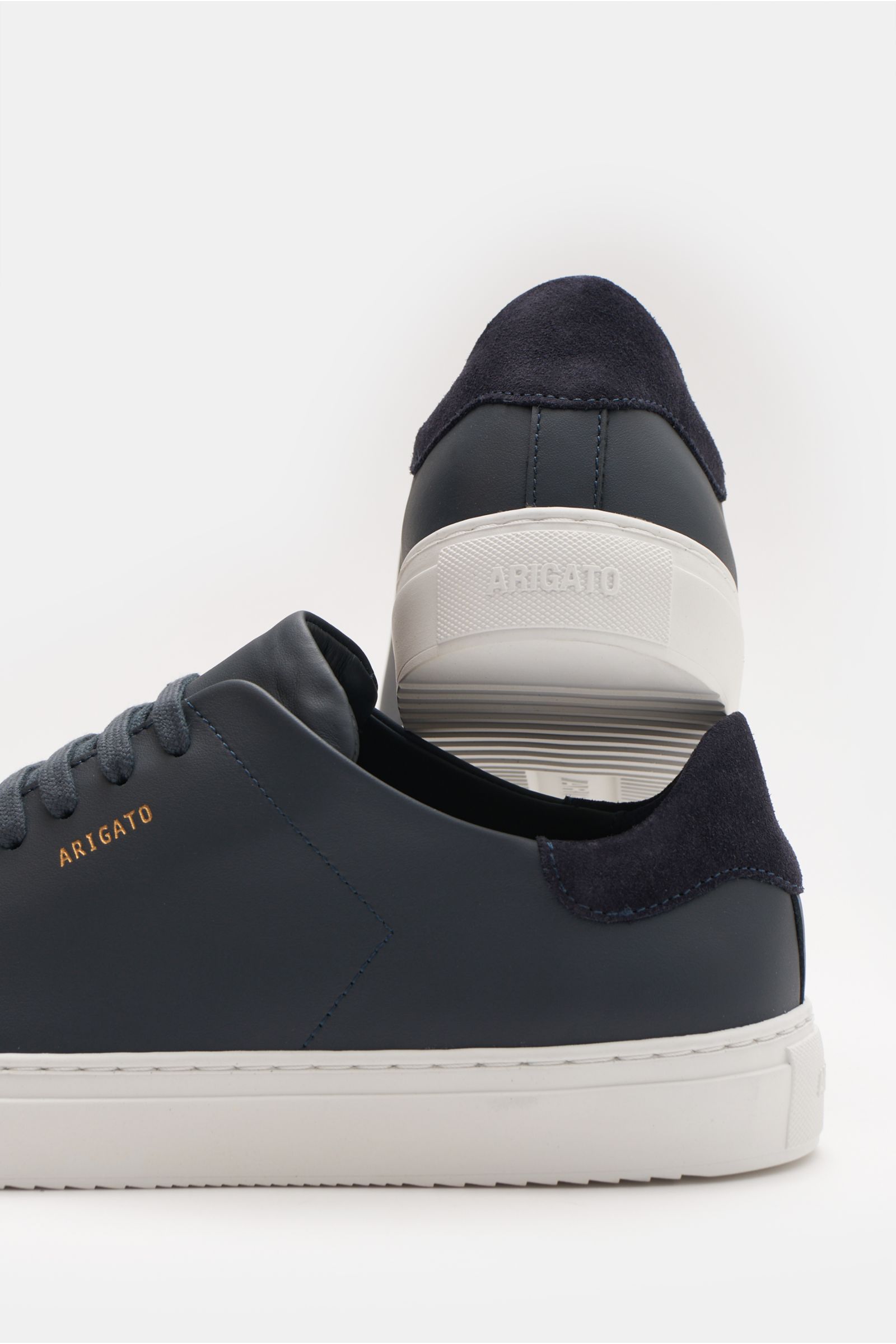 Axel Arigato Sneaker 'Clean 90' navy aus Glattleder mit Veloursleder-Detail, runder Vorderkappe, Sieben-Loch-Schnürung, goldfarbener Prägung, gepolstertem Schaftrand, Lederfutter und flexibler Gummisohle, fotografiert aus seitlicher Nahaufnahme mit Blick 
