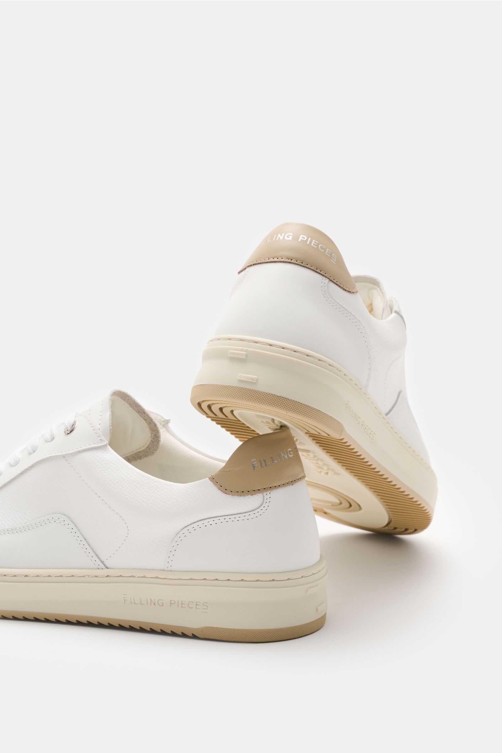 Side and rear view of Filling Pieces Sneaker 'Mondo Crumbs' weiß in white with beige heel tab, fine grained leather, round toe, six-eyelet lacing, padded collar, microfiber lining, and flexible rubber sole. Legerer Allrounder: Der FILLING PIECES Sneake