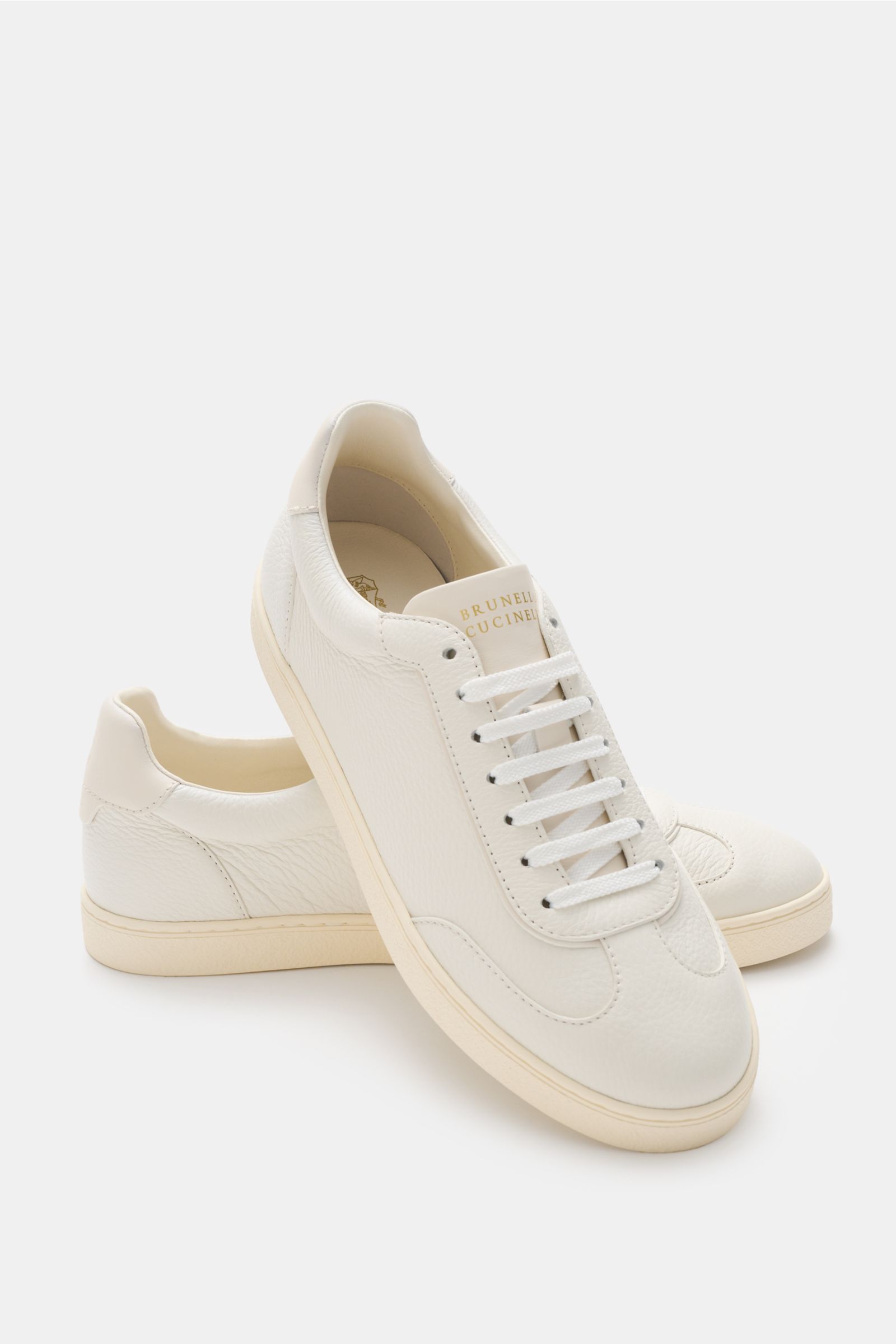 Brunello Cucinelli Sneaker creme aus geschmeidigem Leder, schmal zulaufend, retro, von oben seitlich fotografiert mit Flügelkappe, Logo und Naturgummisohle.