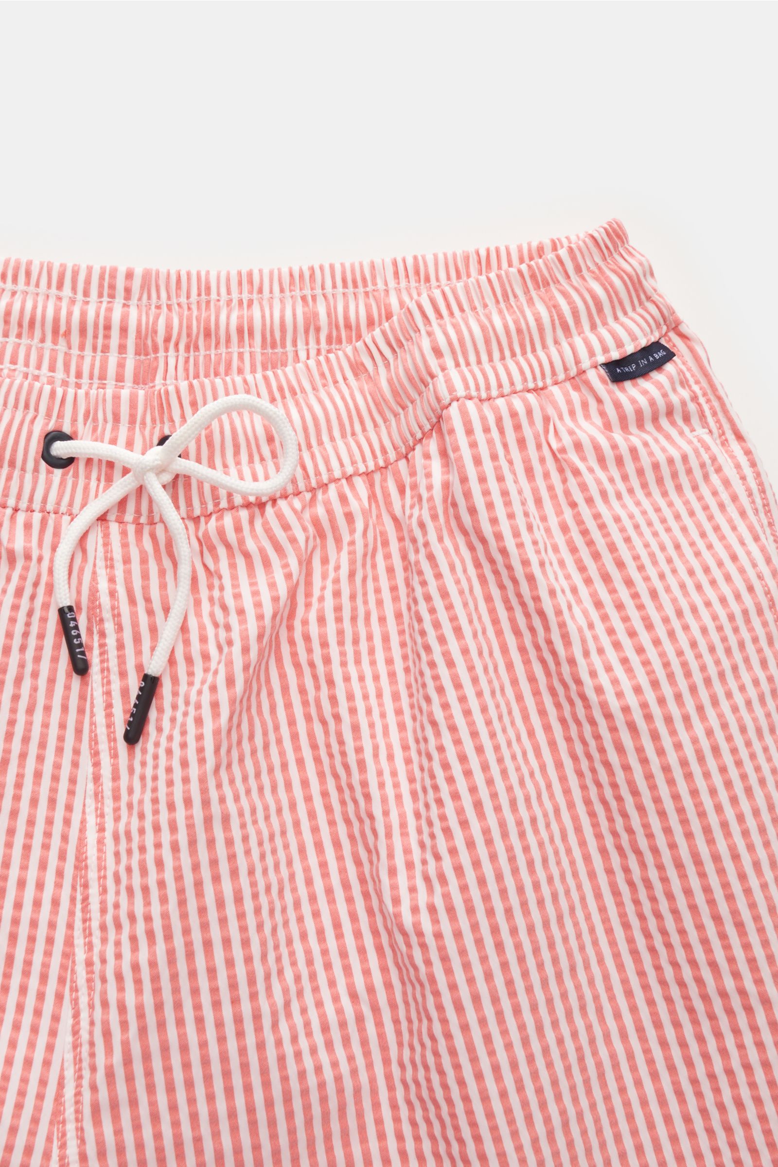 Close-up front view of 04651/ A trip in a bag Seersucker swim shorts 'Seersucker Swim' orange/white striped with elastic waistband and drawstring.

You'll be perfectly prepared for a dip in the sea or the pool in the 'Seersucker Swim' swim shorts by 04651