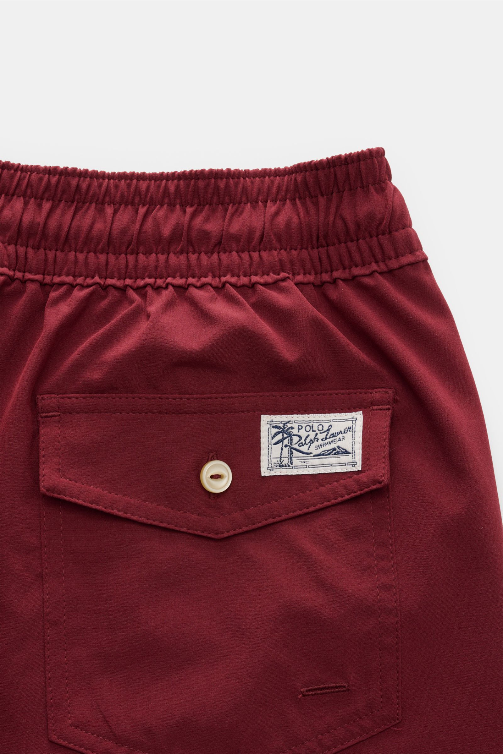 Close-up rear view of Polo Ralph Lauren Badeshorts 'Traveler' bordeaux with elastic waistband, buttoned back pocket, and logo patch.

Stilsicher auf Reisen: Die POLO RALPH LAUREN Badeshorts ist der perfekte Begleiter für den nächsten Urlaub in der Sonn