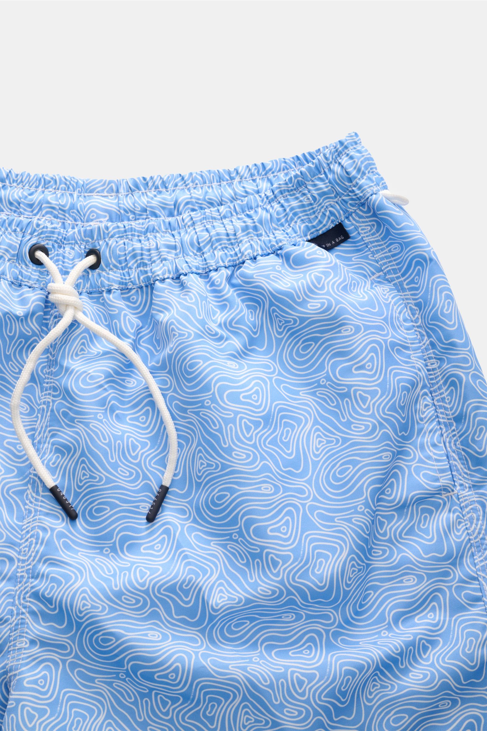 Close-up front view of 04651/ A trip in a bag Badeshorts 'Seamap' blau/weiß gemustert with elastic waistband, white drawstring, and blue-white quick-dry microfiber fabric featuring a nautical map pattern.