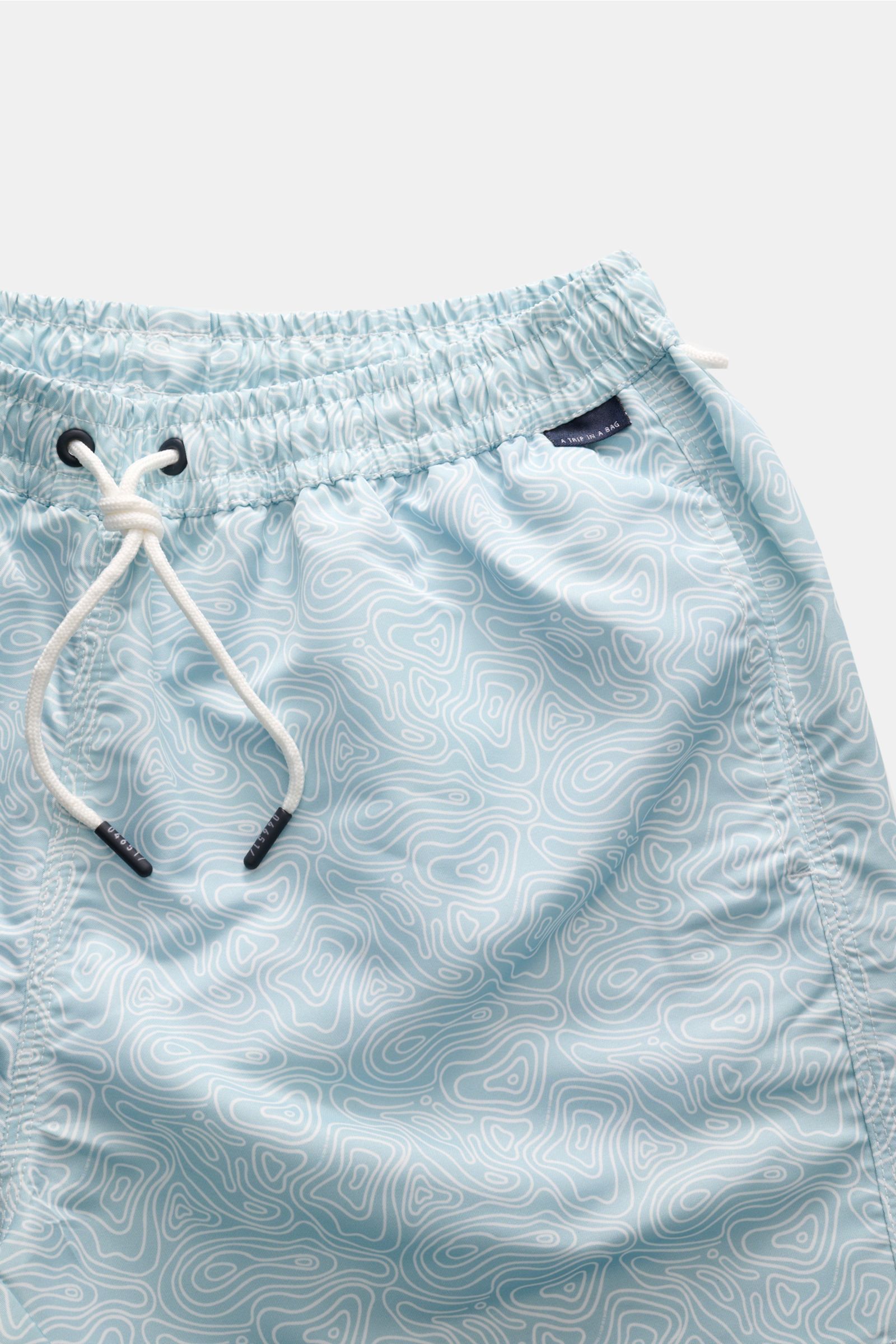 Close-up front view of 04651/ A trip in a bag Badeshorts 'Seamap' mint/weiß gemustert with elastic waistband, white drawstring, and quick-drying microfiber featuring a white contour map pattern.