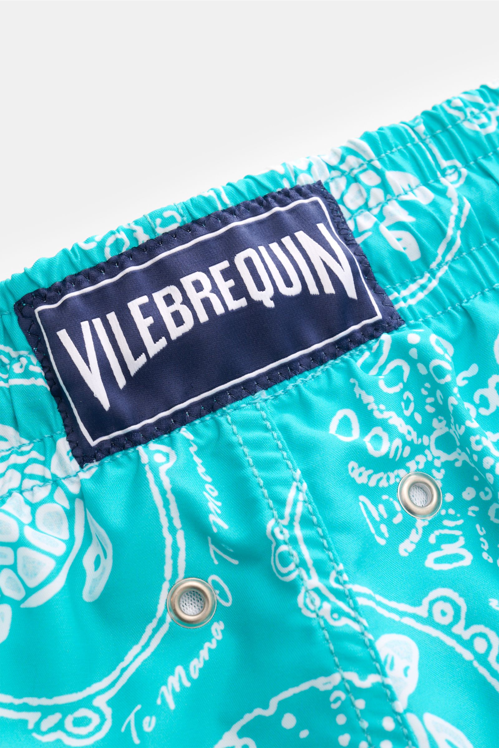 Close-up rear view of Vilebrequin Swim shorts 'Moorea' turquoise/white patterned, showing elastic waistband, VILEBREQUIN label, drainage eyelets, and detailed print. The swim shorts 'Moorea' by VILEBREQUIN feature a distinctive print and are made of high-