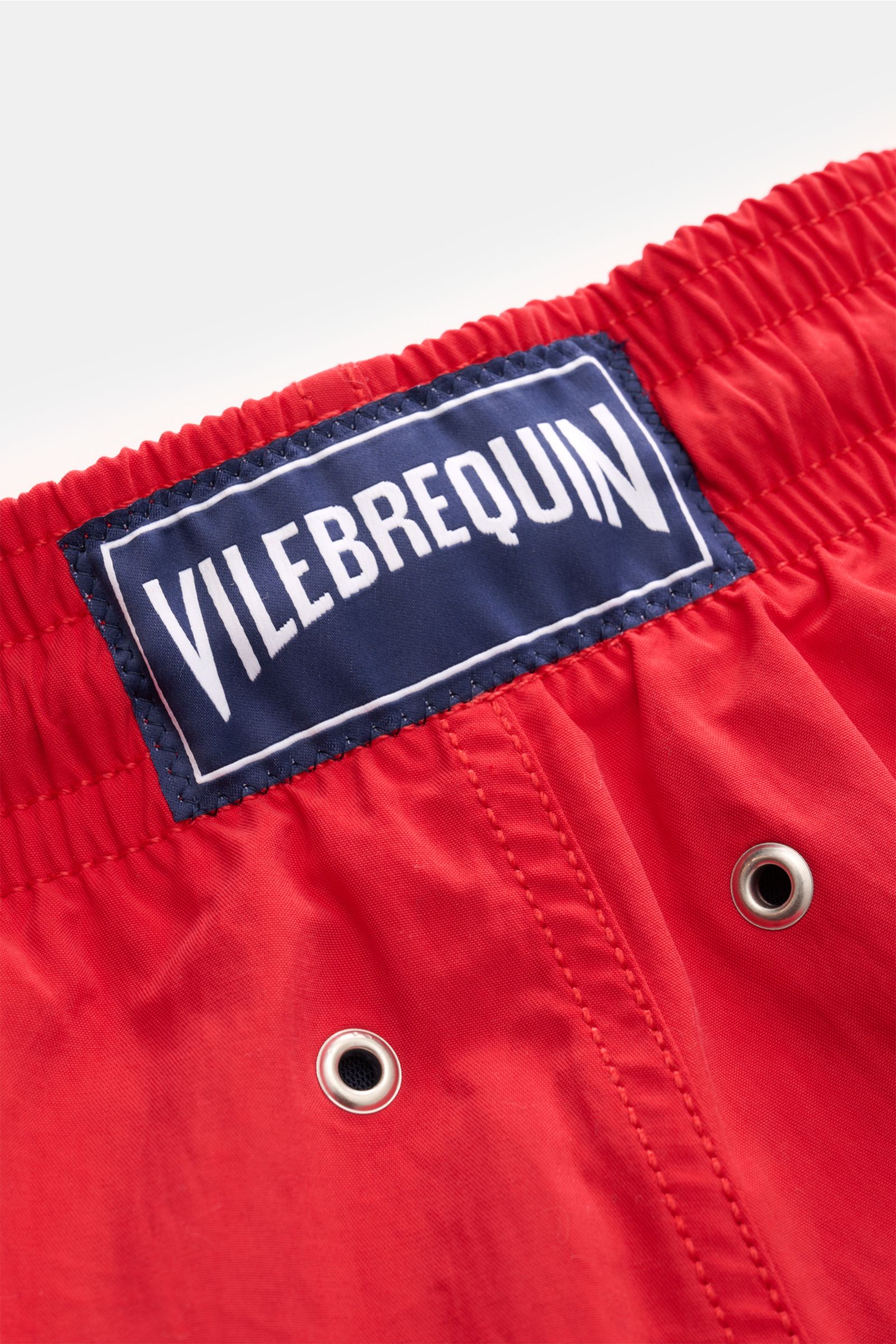 Nahaufnahme der roten Vilebrequin Badeshorts 'Moorea Magic' von hinten, elastischer Bund, VILEBREQUIN-Label, Entwässerungsösen, hochwertige Microfaser, Farbwechsel im Wasser.