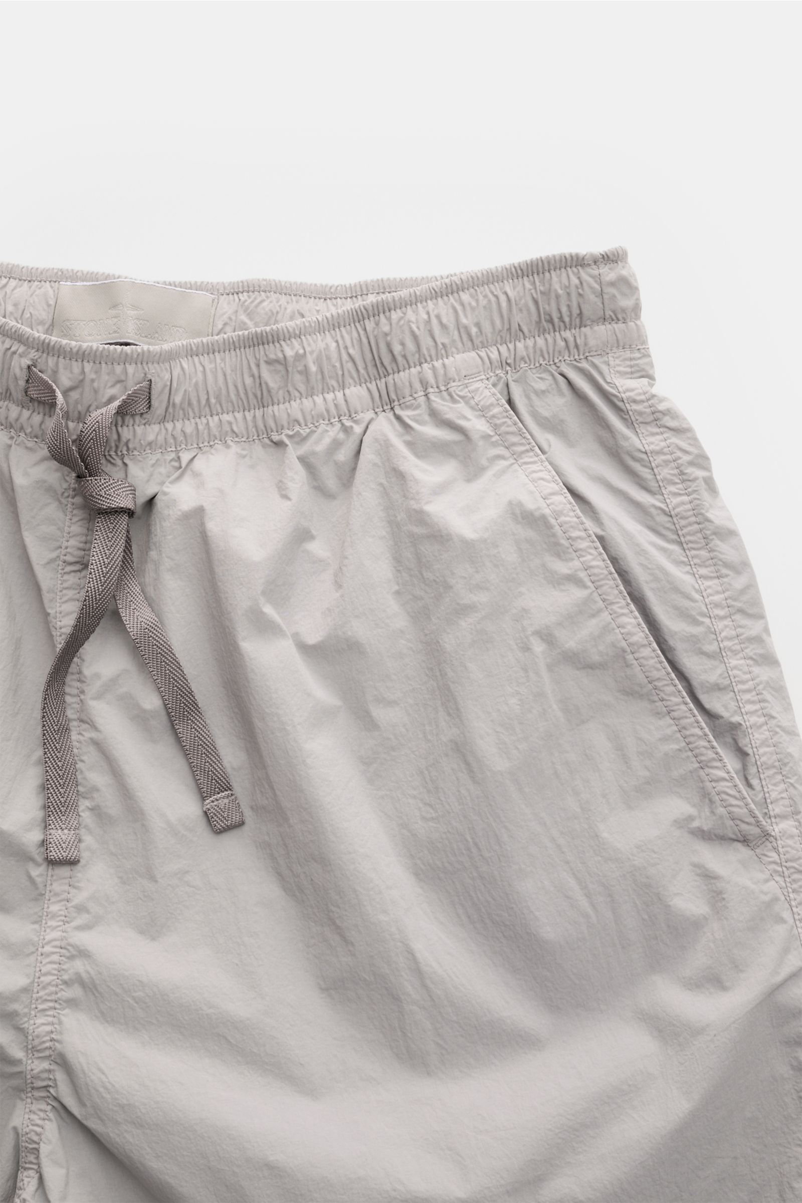 Top-front close-up view of Stone Island Swim shorts 'Ghost Piece' grey featuring an elasticated waistband with drawstring and French pockets.

A monochrome look in classic STONE ISLAND style: on the beach or at the pool, these swim shorts from the 'Gho