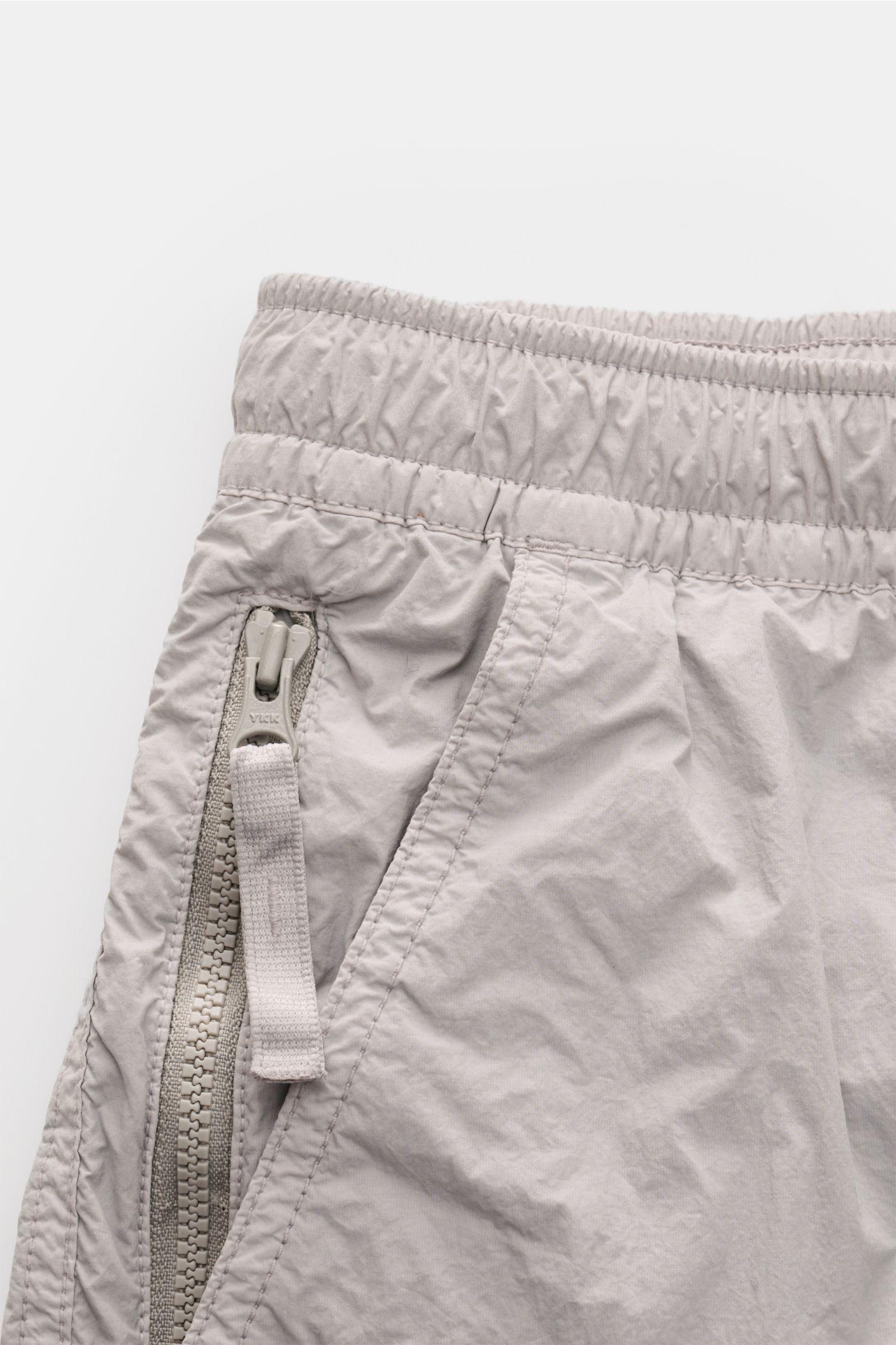 Close-up side view of Stone Island Swim shorts 'Ghost Piece' grey showing elasticated waistband, side zip pocket, and microfibre fabric.

Description: A monochrome look in classic STONE ISLAND style: on the beach or at the pool, these swim shorts from 