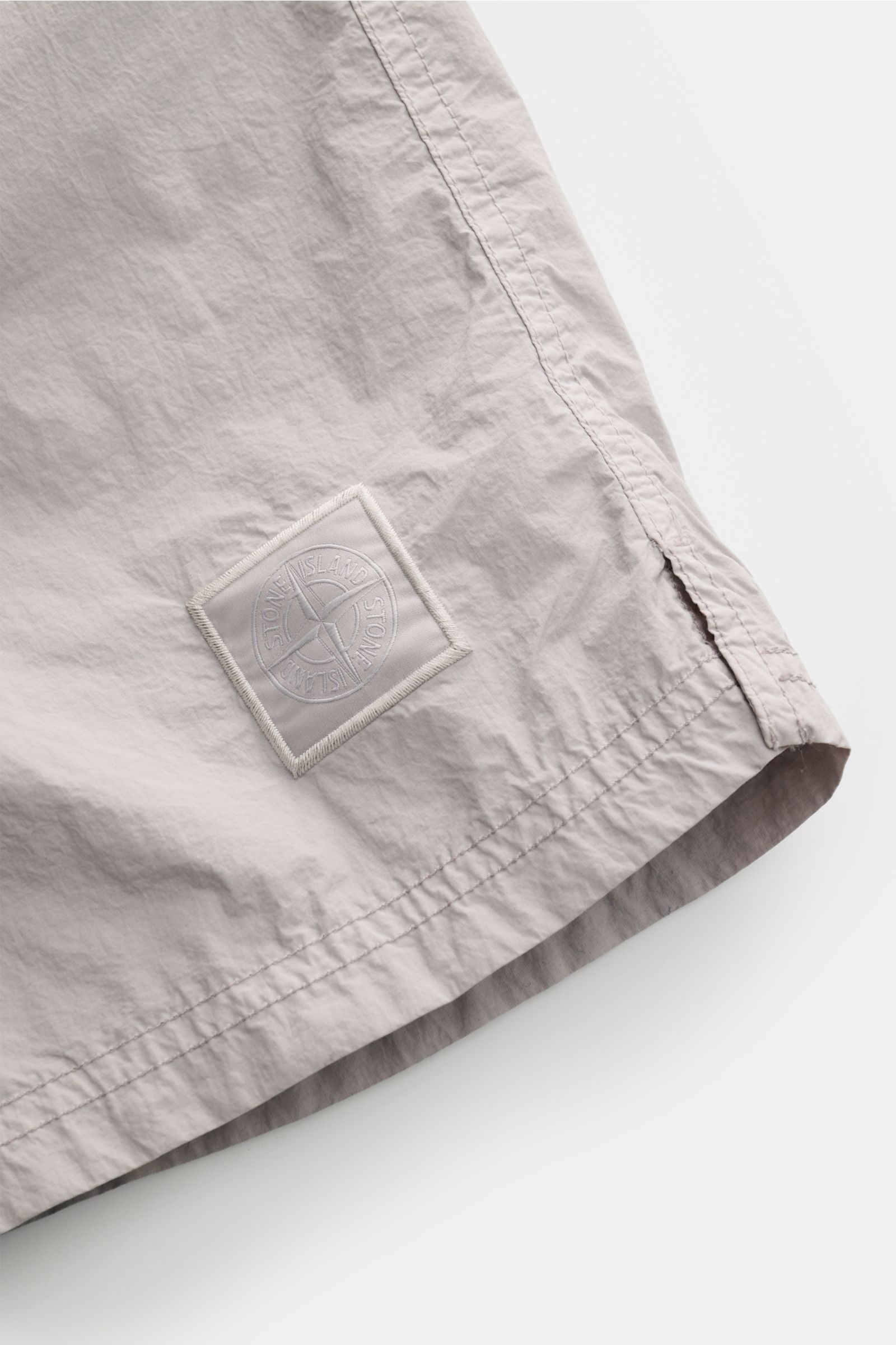 Stone Island Swim shorts 'Ghost Piece' grey close-up from side angle showing logo patch, microfibre fabric, and hem details.  

A monochrome look in classic STONE ISLAND style: on the beach or at the pool, these swim shorts from the 'Ghost Collection' 