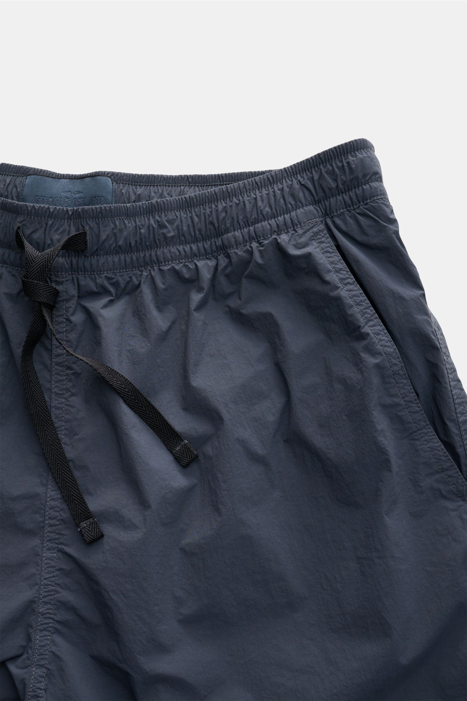Stone Island Badeshorts 'Ghost Piece' graublau, frontale Nahaufnahme, Regular Fit, Microfaser, elastischer Bund, Zipper-Taschen, Mesh-Futter, monochromes Weblabel.