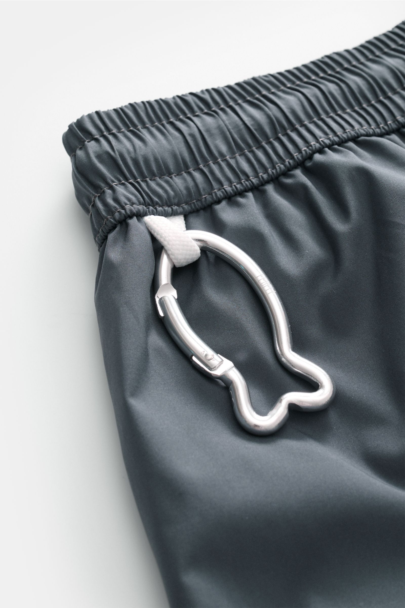 Fedeli Swim shorts 'Madeira Airstop' dark grey elasticated waistband close-up with whale-shaped carabiner, photographed from above.

The swim shorts 'Madeira Airstop' by FEDELI are a timeless model for your suitcase. With their comfortable elasticated 